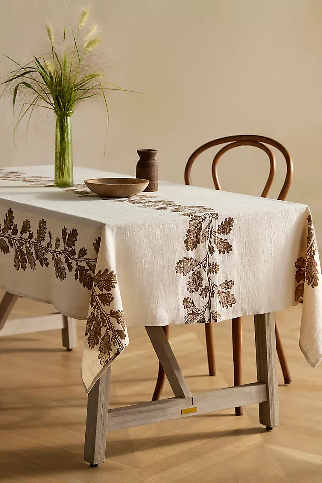 A cream linen tablecloth patterned with brown oak leaves