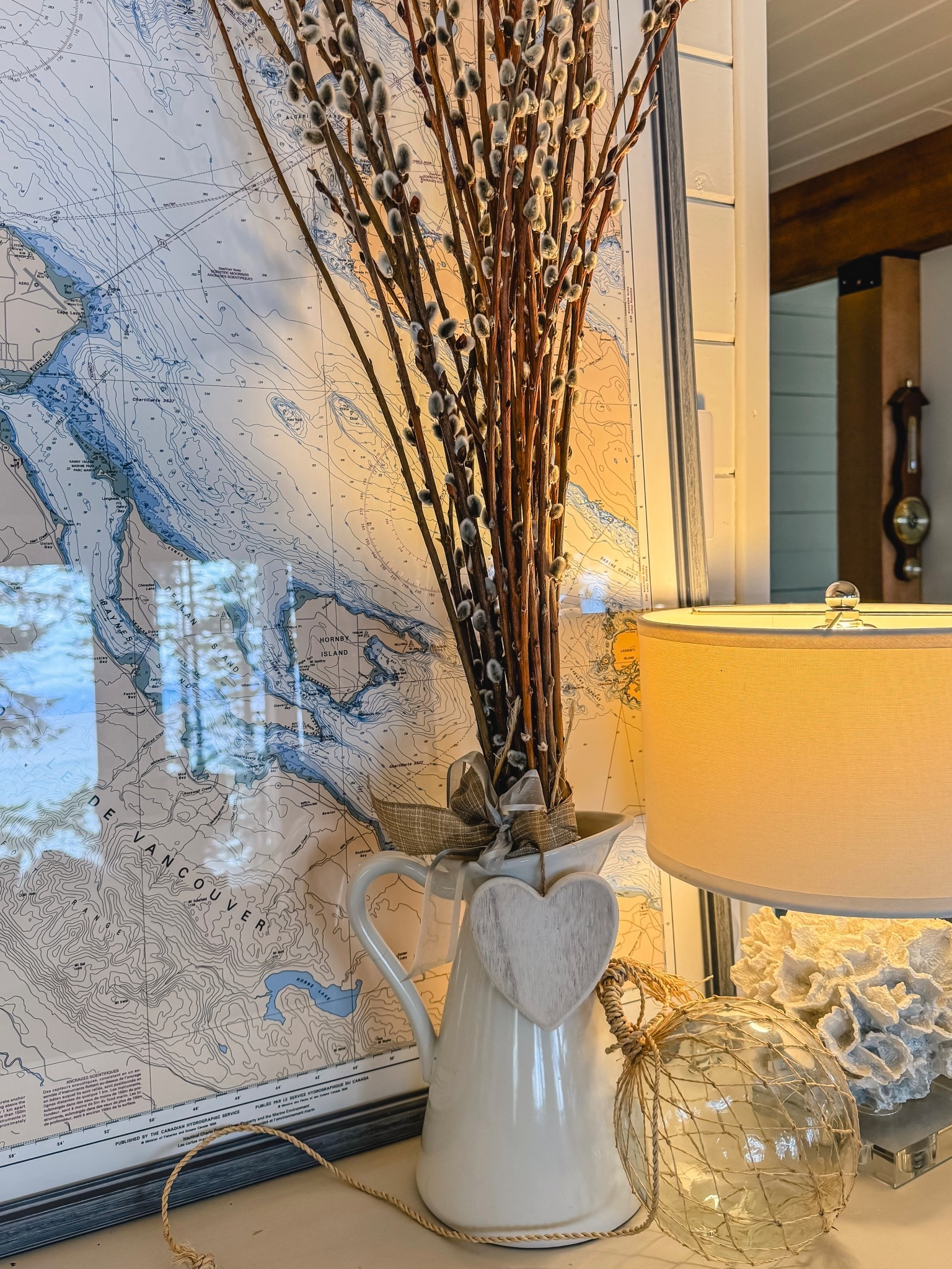 Cozy cottage winter decorating  Pussy willows in a white pitcher instantly transitions your decor from Christmas to winter whites. And the glass fishing float, nautical chart and coral lamp lend an instant coastal vibe. Which of course is my jam  

#LTKhome #LTKstyletip #LTKwinter