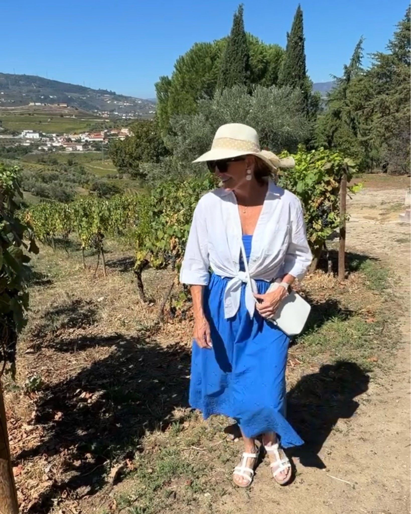 Blue Midi Dress for a European Vacation

I wore this beautiful blue dress for a Douro valley vineyard visit in Portugal, styled with a white shirt tied at the waist, sandals, and a sunhat. A simple styling tip for your next trip: layer a button-down over a dress to create another look without packing another outfit.

#travelstyle #fashionover50 #mididress #vacationoutfits #portugalstyle