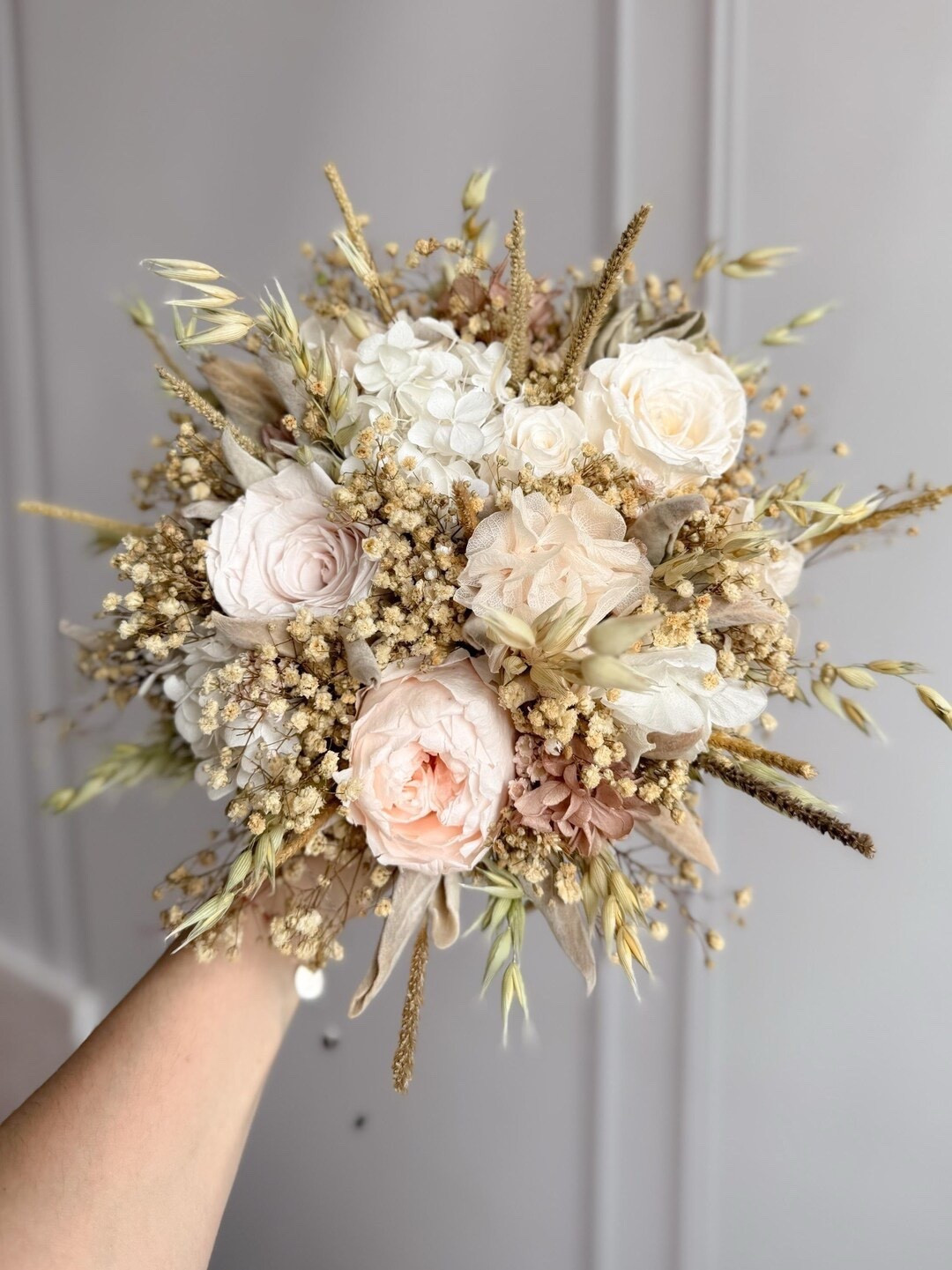 This dried wildflower bridal bouquet blends preserved roses, baby’s breath, hydrangea, and delicate oats in soft shades of blush, ivory, and nude. The romantic palette and airy texture create a timeless, rustic look that’s perfect for boho or garden-inspired weddings. Crafted with preserved blooms, this bouquet stays beautiful long after the celebration, making it a meaningful keepsake from your special day. #ltkbride #ltkhome #bridalbouquet #bohowedding #rusticwedding #driedflowers #preservedflowers #weddinginspiration #bohobride #weddingdetails

#LTKWedding #LTKSeasonal #LTKHome