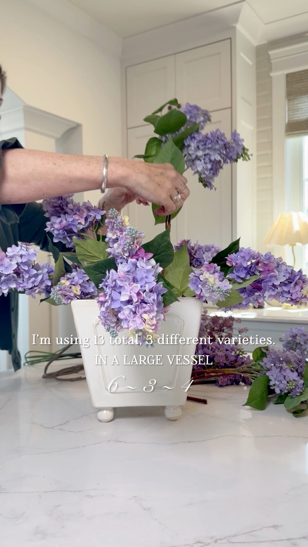 Rather than using all the same, try mixing your faux lilac stems. Mixing creates a gorgeous variation of color. This is a large vessel. I’m using 13 lilac stems (6, 3, 4), a mix of premium and budget friendly. I also added a seed stem for interest — 4 of those.

#LTKSeasonal #LTKvlog #LTKHome