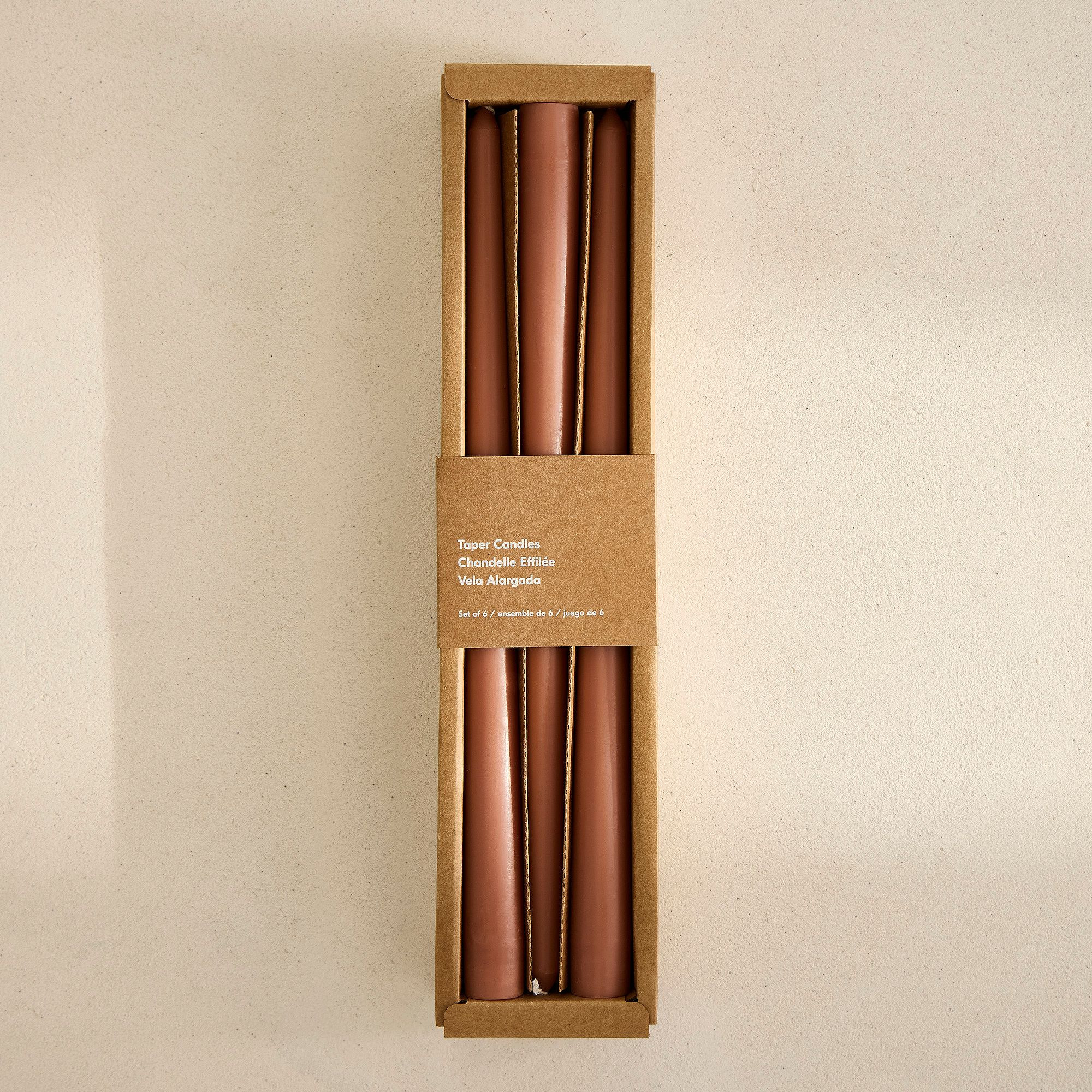 A boxed set of clay-colored taper candles