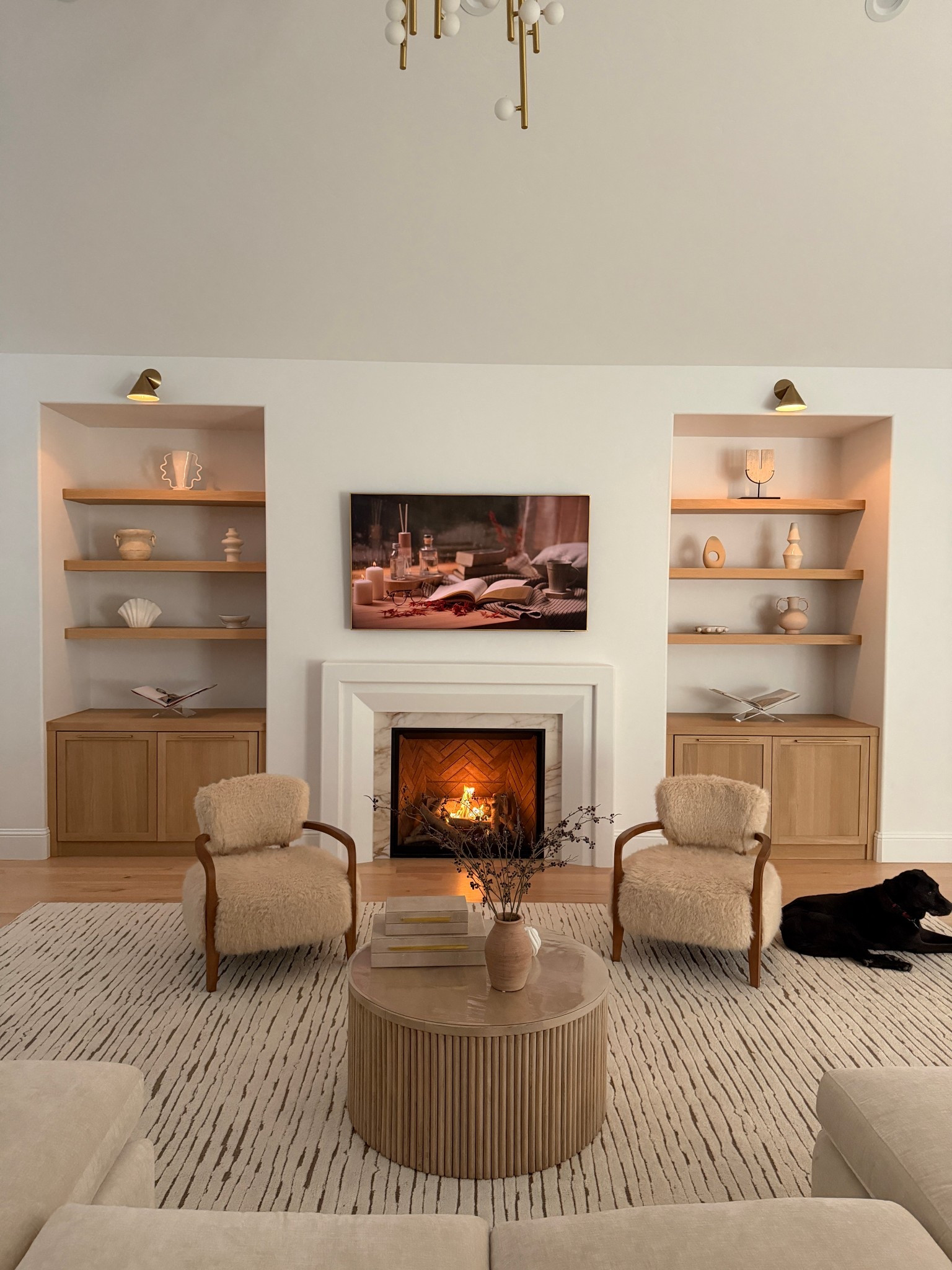 White oak shelves with pottery and vases. Love this neutral area rug with fur chairs to cozy around the fire. Fluted coffee table 

#LTKHome