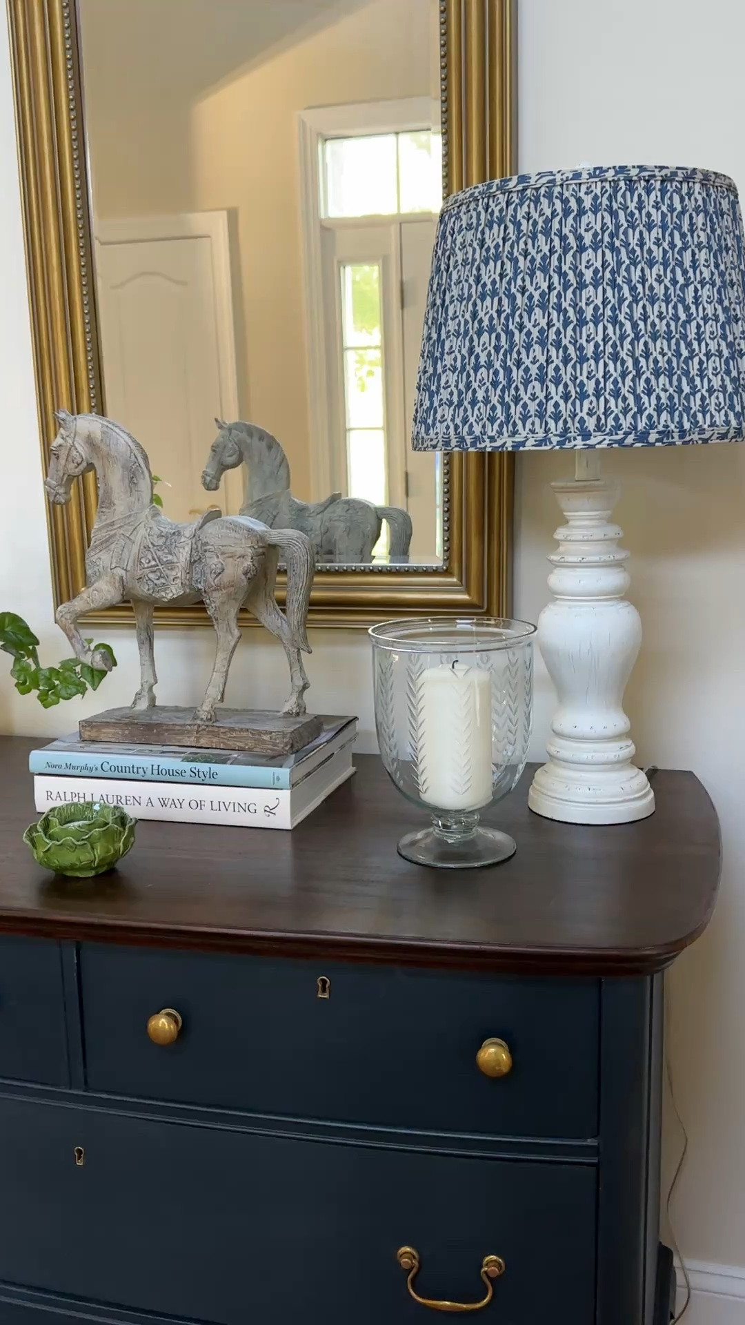 Spring refresh for the entryway.  Blue pleated lampshade, stack of books, classic horse statue, cabbage ware candle holder.

#LTKHome #LTKSeasonal