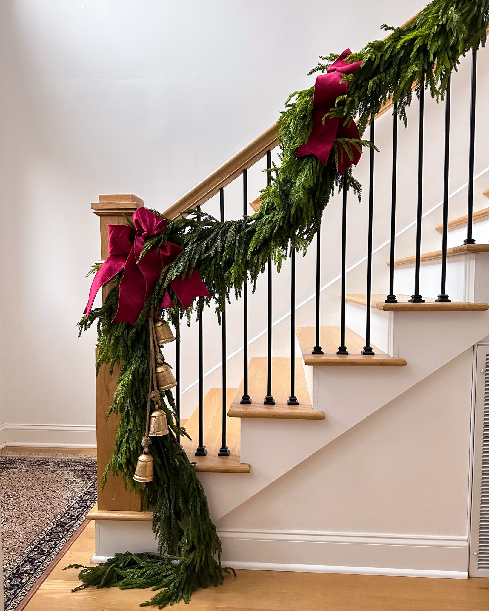 Garland and a thick velvet burgundy ribbon is all you need. I kept the staircase simple this year, layering  Norfolk pine garland and adding a couple extra pieces at the base. What I used: 2 x deluxe Norfolk pine along the entire banister. 2 extra pieces at newel post. Burgundy ribbon twisted into bows and bells at the base. #christmasdecor #garland #holiday 

#LTKSeasonal #LTKHome #LTKHoliday