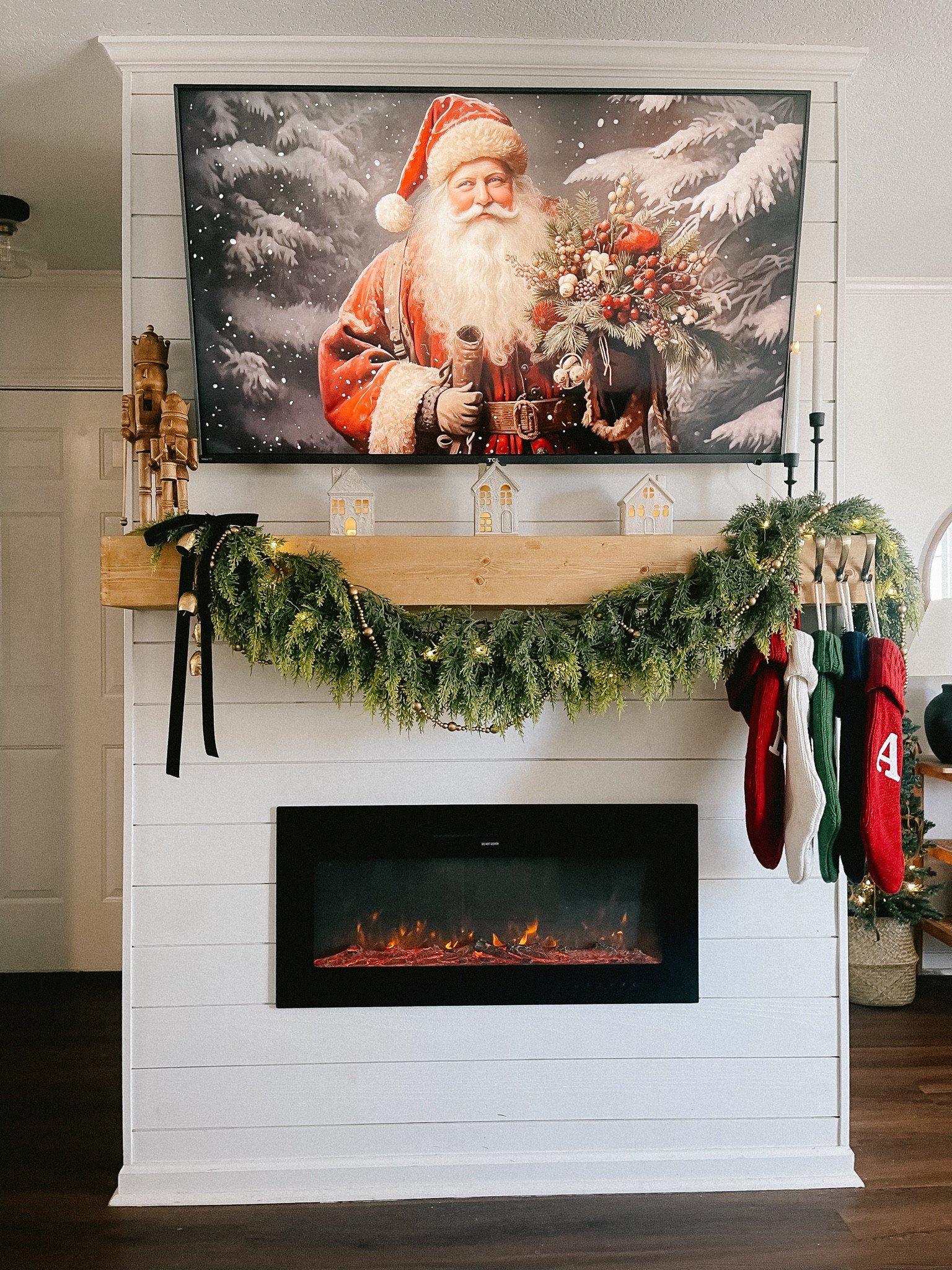 Christmas fireplace mantle decor. Christmas garland. Nutcrackers. Traditional stocking. Velvet ribbon bows. Fairy lights. Candle stick holder. Battery operated candles. Ceramic Christmas house village. Electric fireplace. 

#LTKHoliday #LTKhome 

#LTKSeasonal