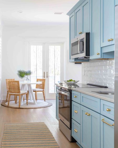 Our carriage house kitchen with Aero Blue cabinets, brass cabinet hardware, a blue striped jute rug and simple white subway tile. You can also see the little dining room with a round white dining table, rattan dining chairs, round jute rug, and faux fab palms! Take the full tour of the carriage house here: https://lifeonvirginiastreet.com/florida-new-build-progress-part-iii/.
.
#ltkhome #ltksalealert #ltkseasonal #ltkfindsunder50 #ltkfindsunder100 #ltkstyletip

#LTKhome #LTKSeasonal #LTKsalealert