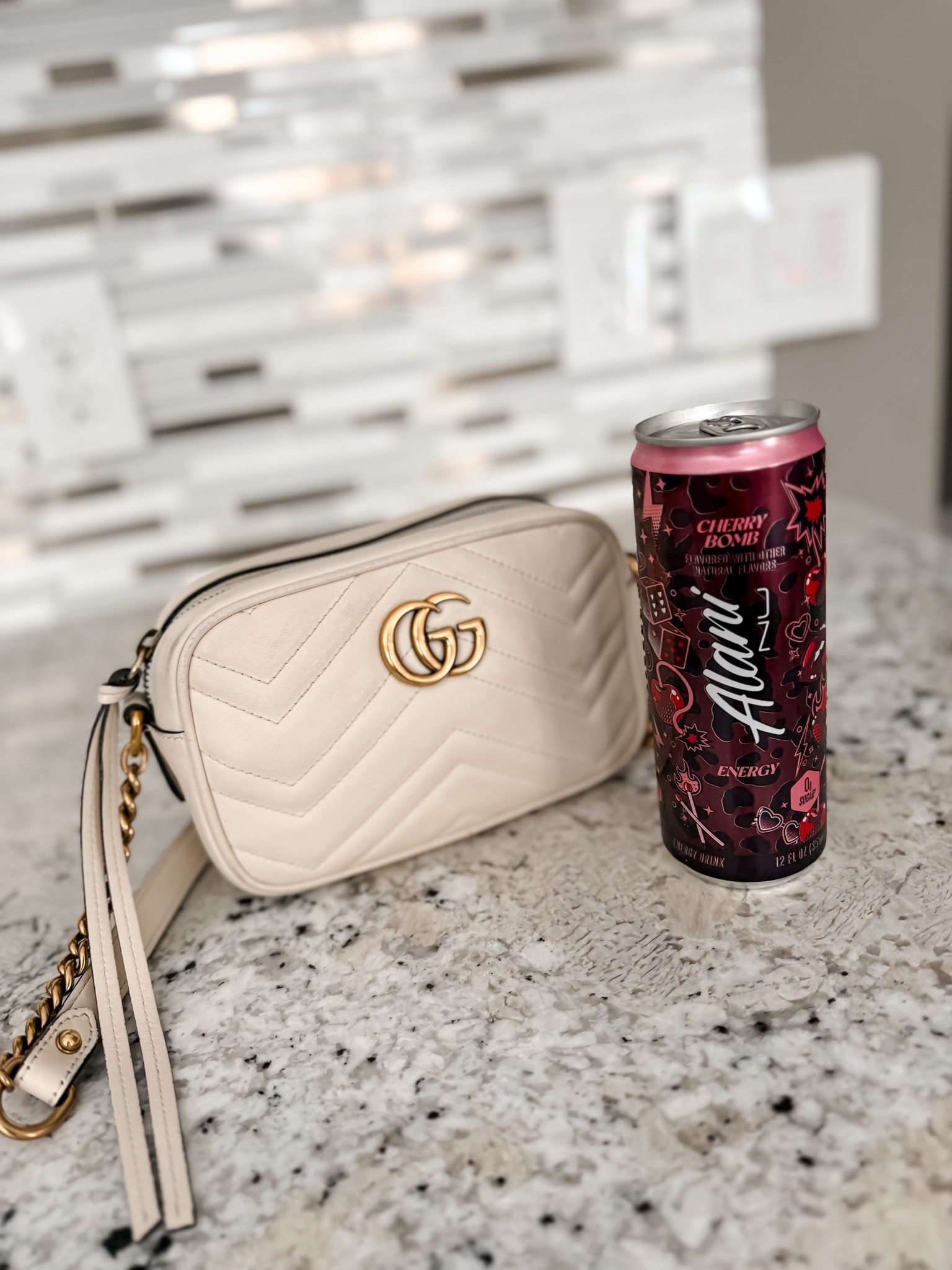 White leather Gucci crossbody designer bag and Alani nu cherry bomb energy drink 
