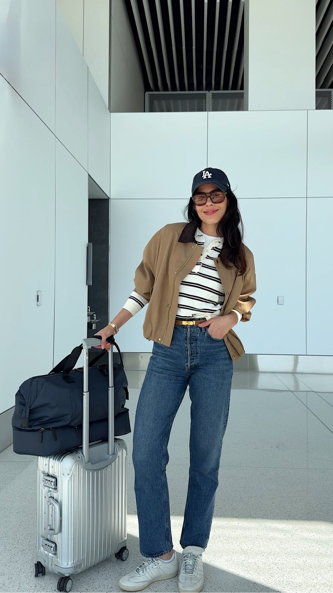 Airport Fit Check ✈️ Be honest… are you team jeans or team sweats at the airport? 
Spring outfit with a bubble bomber featuring the cutest corduroy collar, layered over a classic striped long sleeve polo, paired with my go-to straight-leg denim, a baseball cap, and my new carry-on bag.