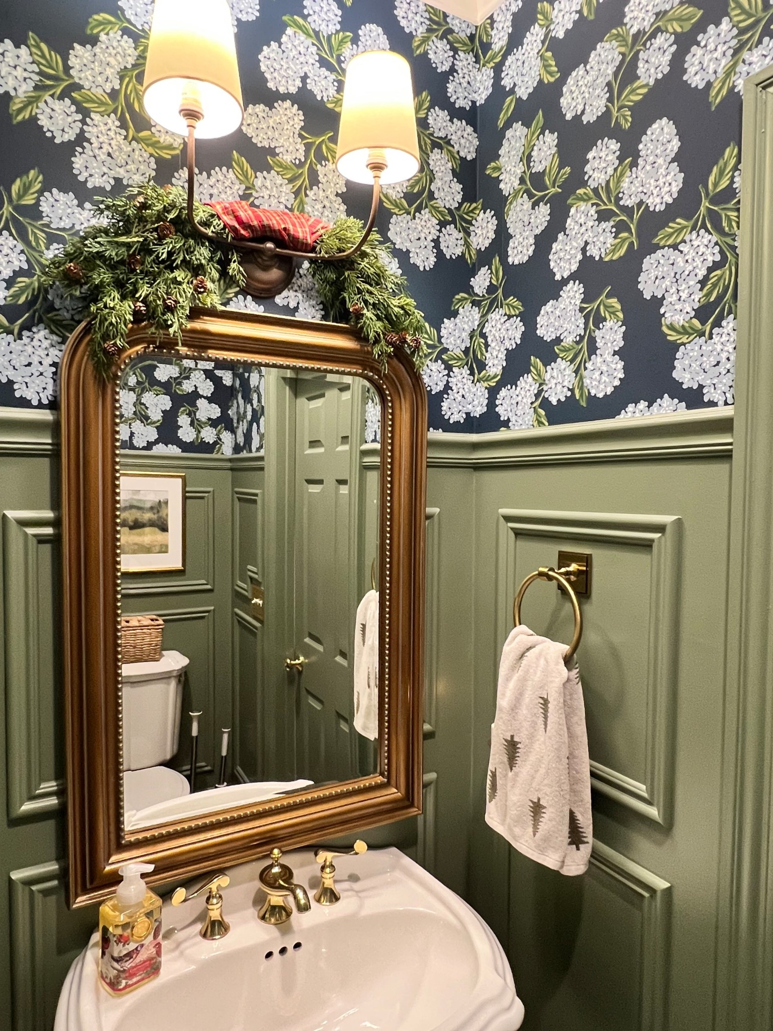 Sometimes it’s the smallest spaces that bring the most Christmas cheer. ✨ I added a sweet little swag of garland to our powder room sconce, tied it up with classic red plaid ribbon, and sprinkled in a few festive touches, like Christmas soap and the cutest reversible pine tree hand towel. It’s simple, quick, budget-friendly… and honestly? It makes the whole room feel like so festive. ❤️💚

#LTKHome #LTKHoliday #LTKFindsUnder50