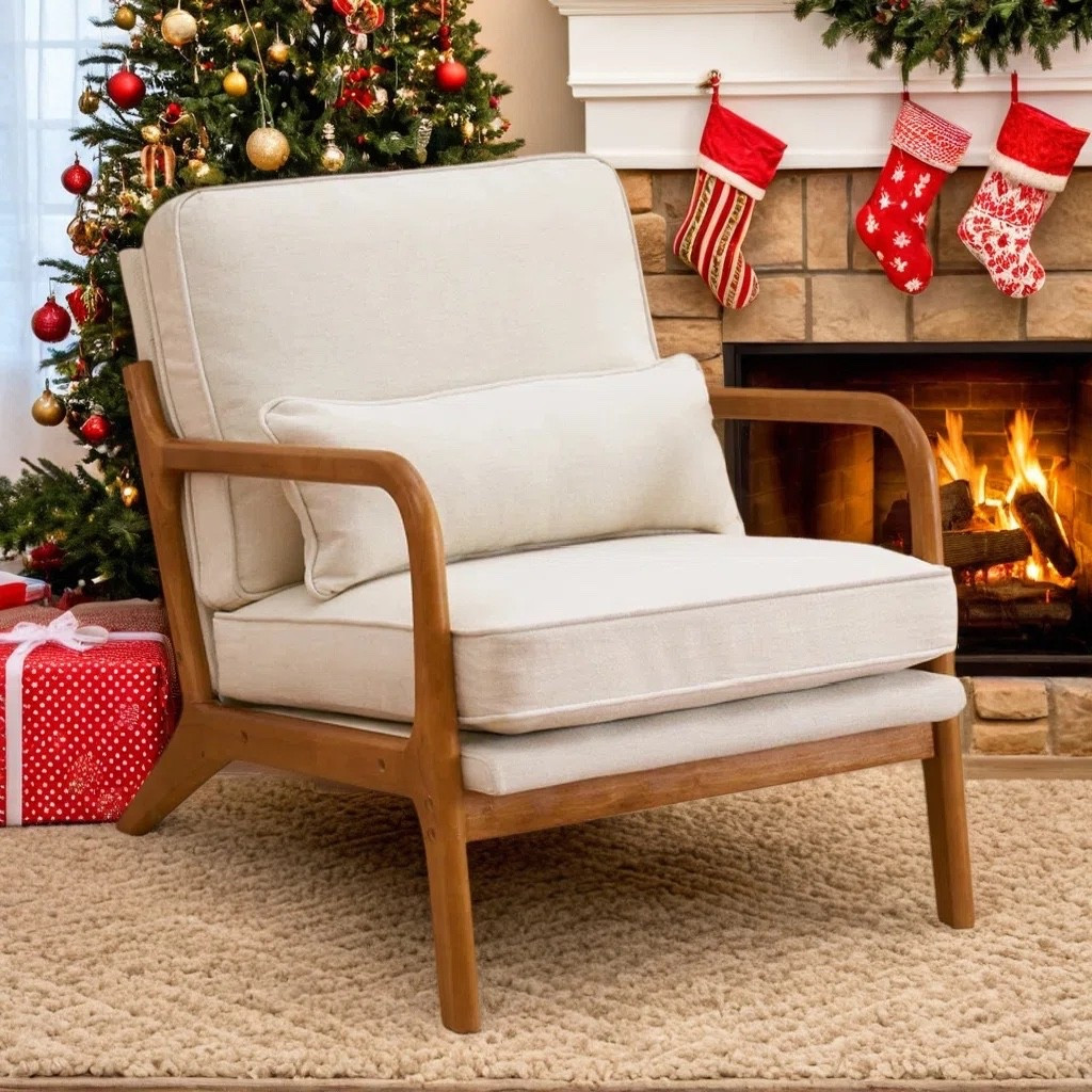 This warm holiday nook features a soft cushioned wood-frame accent chair styled with a plush neutral rug, a glowing fireplace, and a festive Christmas tree. It creates the perfect cozy corner for seasonal lounging and winter decorating inspo. The exact chair is tagged, as well as some similars 