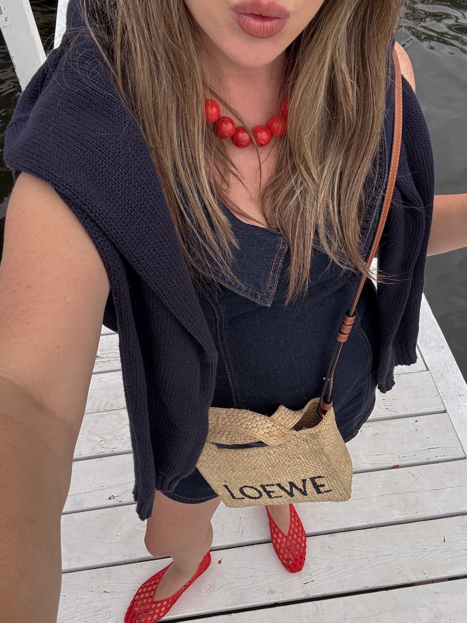 Summer dresses 🤍 Wearing a  denim dress with a navy knit sweater draped over the shoulders, red mesh flats, statement red bead necklace, and my Loewe raffia crossbody bag. The perfect casual chic outfit for lake days, vacations, weekend brunch, and European summer style. #LTKStyleTip #SummerStyle

#LTKSeasonal