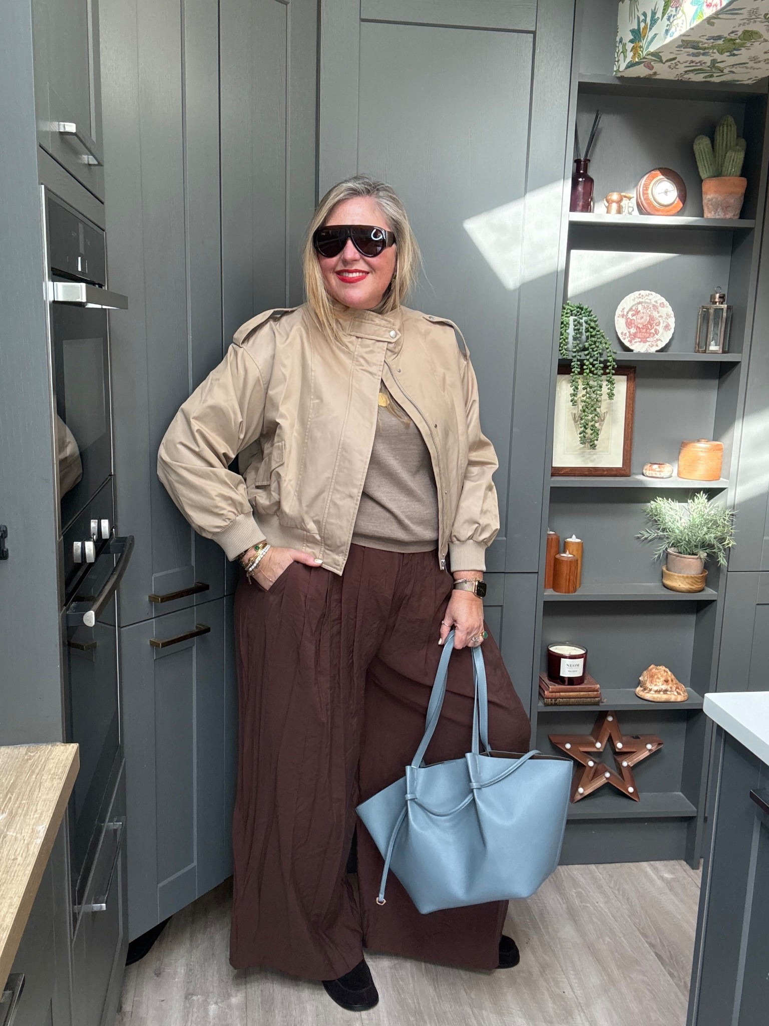 Brown palazzo trousers, beige Rollneck jumper, beige bomber jacket, brown sunglasses, brown loafers, blue tote bag 

#LTKover50style #LTKplussize #LTKspring