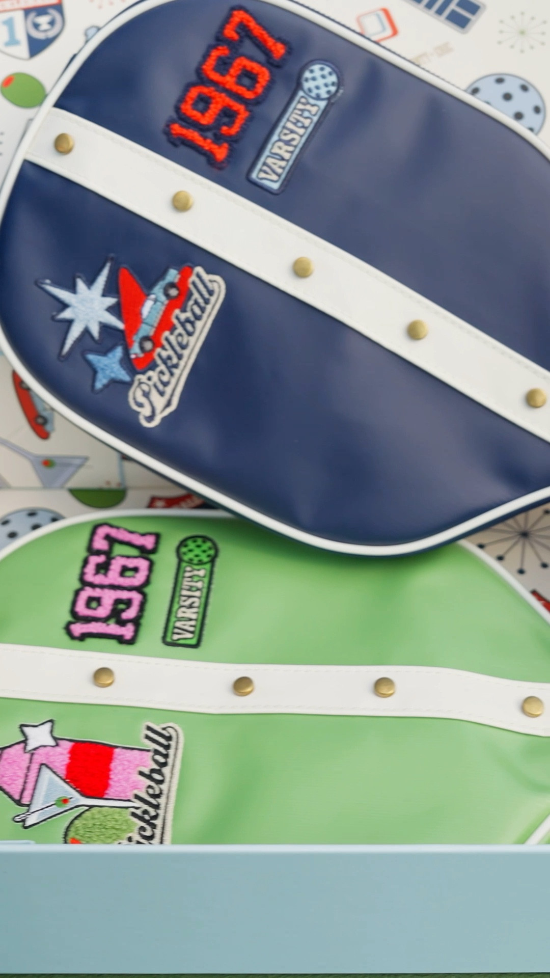 Step into 1960s glamour with the Sainty + Eric Retro Pickleball Set.
 
A statement piece for any occasion from  birthday celebrations to timeless wedding gifts. Each set features two exquisitely crafted paddles with double-sided vintage-inspired designs, two waterproof paddle covers, and two coordinating balls. Finished with faux leather-wrapped handles for a refined, comfortable grip, this set blends sophisticated design with modern playability. Elevate your game and your style with a set destined to turn heads