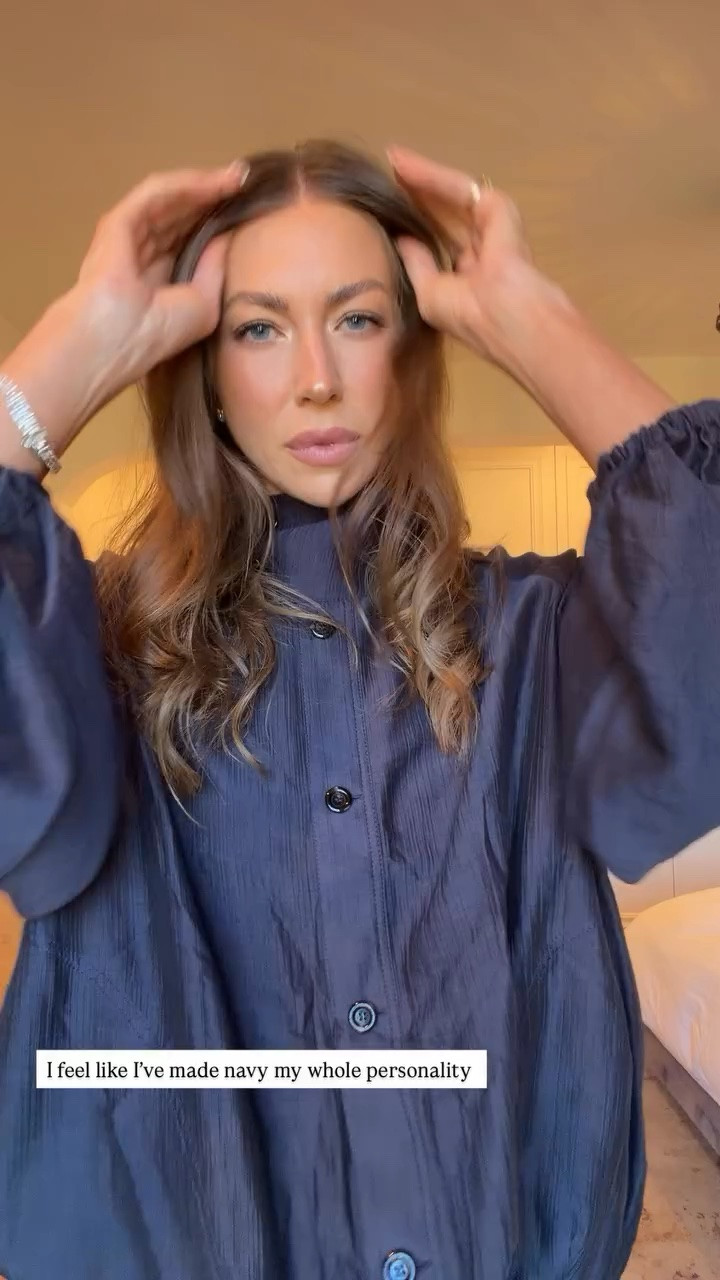 Stassi Schroeder wearing a navy Overshirt crafted from a semi-sheer fluid fabric. Features a high neck and long puff sleeves. Front button closure. Elasticated hem and cuffs with a gathered effect. Made from a fine, lightweight fabric.