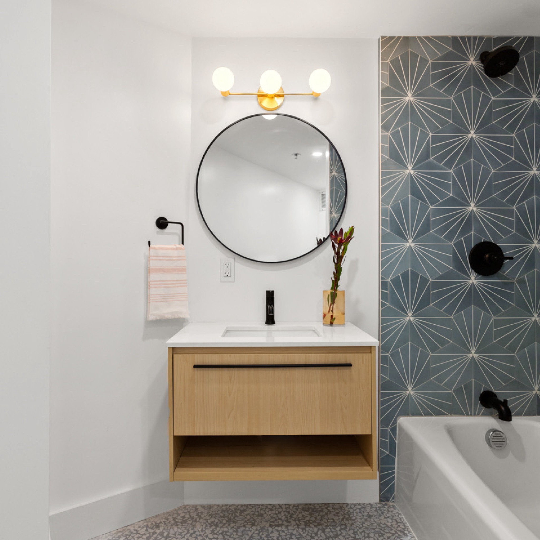 in the guest bathroom at the #goldengirlscondo, we used the same maple wood floating vanity and plumbing fixtures as in the primary bathroom, but opted for a matte black finish. we also used the same terrazzo-look floor tile, in gray…but it was the blue starburst pattern cement tile on the shower walls that really gave this bathroom its own personality. #dwelloctober

#LTKhome