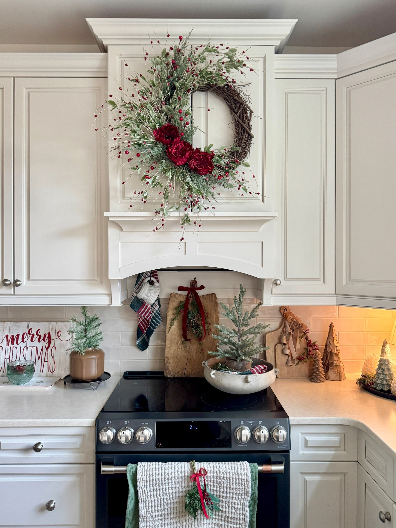 Christmas kitchen! Beautiful 24” winter wreath with greenery, red berries and florals, currently on sale. Green and red plaid napkins, small 12” pine trees on sale for $3.99! Small hanging gold bells, set-of-6 textured clear green glass dessert bowls, the cutest set-of-4 mini swags, pretty waffled towels, bread board, white Santa mug, wooden trees and more  

#LTKHome #LTKCyberWeek #LTKHoliday