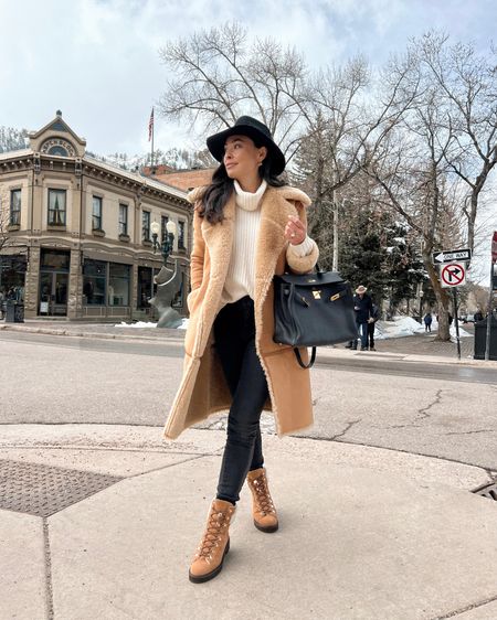 Kat Jamieson wears a shearling coat, black skinny jeans, cream turtleneck winter boots, a fedora hat and Hermes Kelly bag in Aspen. Winter style, cold weather, sweater, booties, designer bag. 

#LTKtravel #LTKshoecrush #LTKitbag
