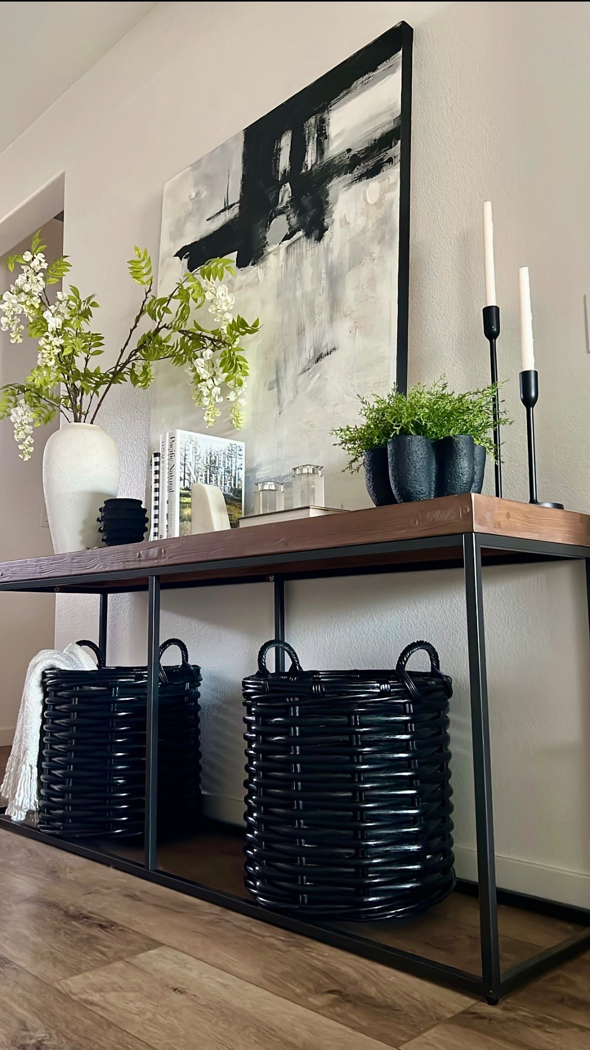 Spring console table. Wood and iron console table, black woven baskets, wisteria branches, white textured vase, black candles, modern abstract wall art, black and white decor 

#LTKSeasonal #LTKHome