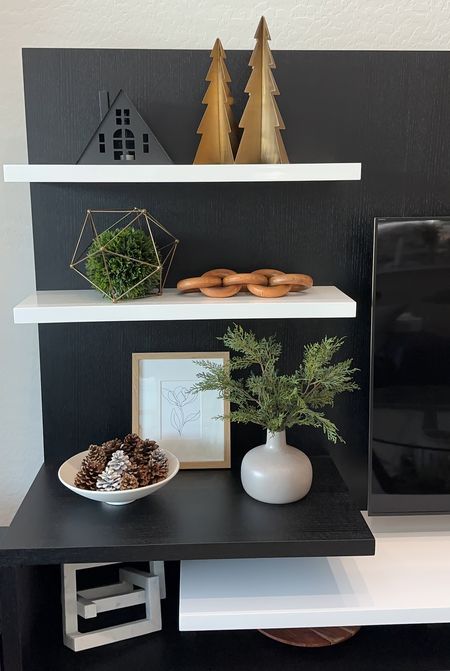 Holiday shelf styling using gold metal Christmas trees, black metal house, wooden links, framed art, bowl of pinecones and faux greenery in a vase! Neutral Christmas decoration. 

#LTKSeasonal #LTKhome #LTKHoliday