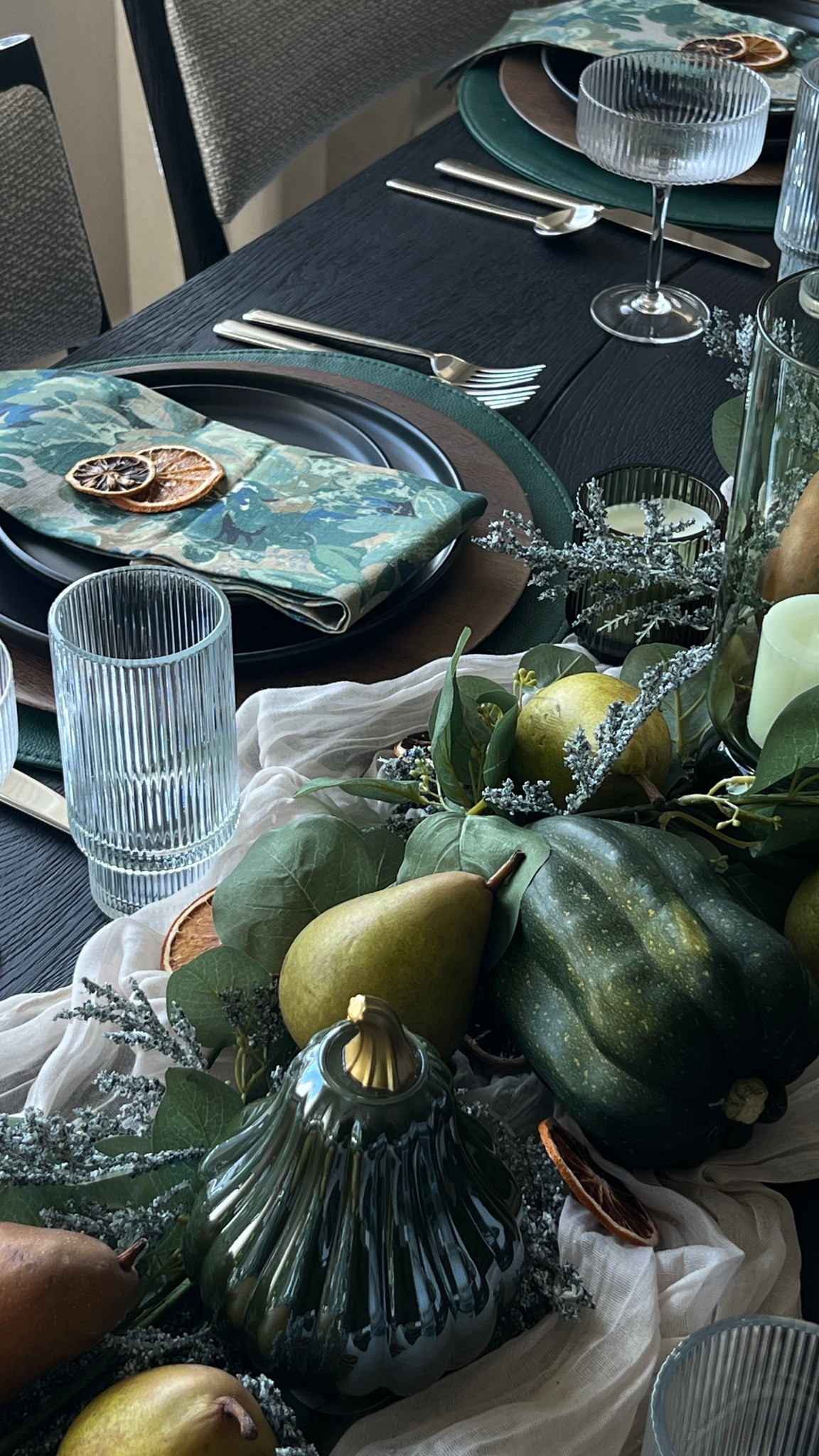 A tablescape for fall hosting or Thanksgiving dinner! Blue and green tablescape decor, moody fall table decor, fruit centerpiece, black dishes, black dining table, green votives, green cylinders, dried fruit decor, dried oranges

#LTKHome #LTKSeasonal