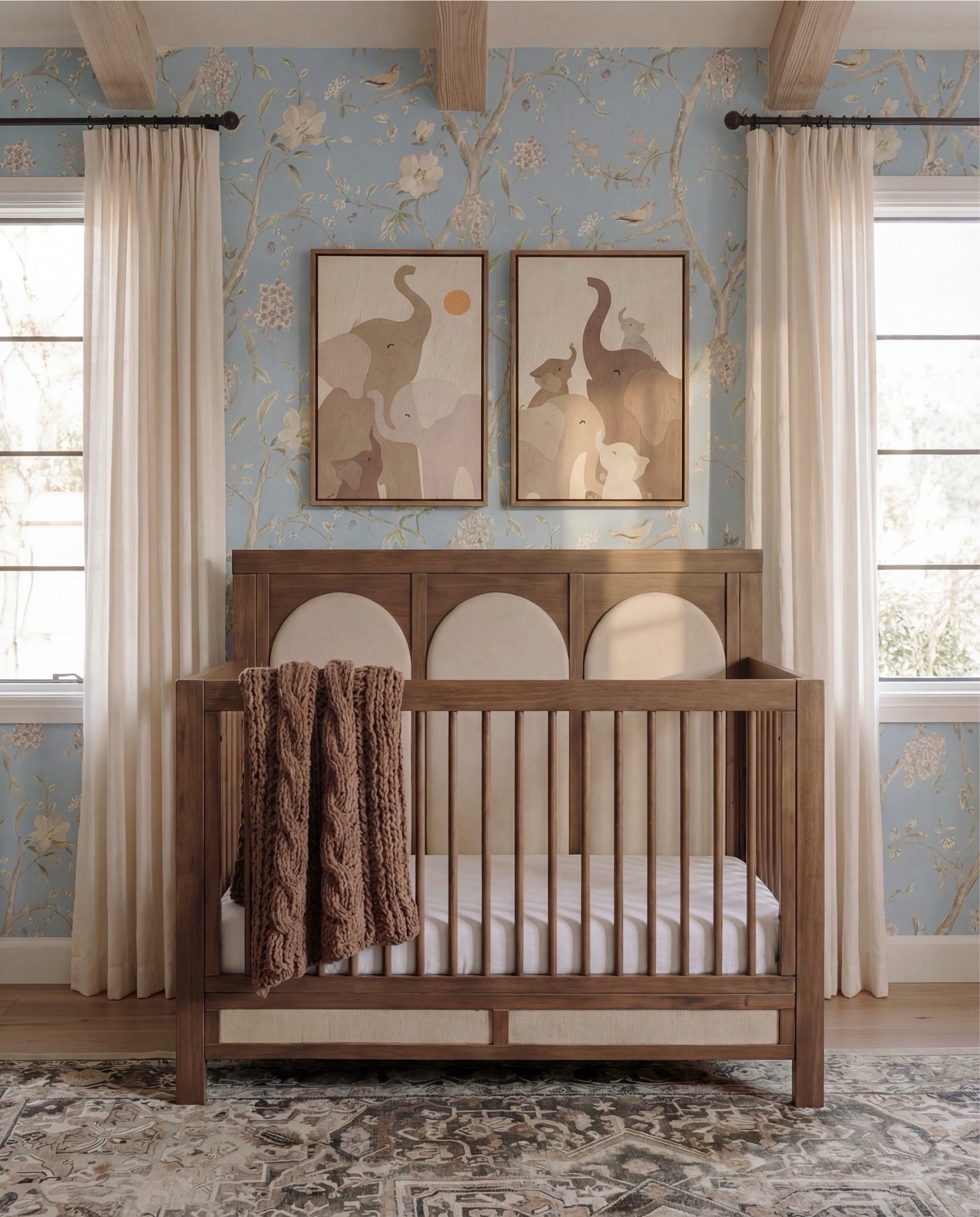 Shop the Look:
• Light blue floral wallpaper
• Natural wood exposed ceiling beams
• Solid wood crib (warm oak tone)
• Neutral crib mattress + fitted sheet
• Knit baby blanket (soft brown)
• Vintage-inspired area rug (muted blue + beige)
• Wood dresser with woven drawer fronts
• Round gold-framed wall mirror
• Brass table lamp with white shade
• White boucle accent chair
• Round upholstered pouf (cream)
• Wooden toy shelving unit
• Front-facing wooden book rack
• Children’s board books (colorful covers)
• Plush teddy bear
• Soft cloud wall decor
• Star-shaped wall pillows (neutral tones)
• Crescent moon wall decor
• Beaded rainbow toy
• Sheer white curtain panels
• Black curtain rod with rings
• Light wood flooring

#LTKSaleAlert #LTKHome