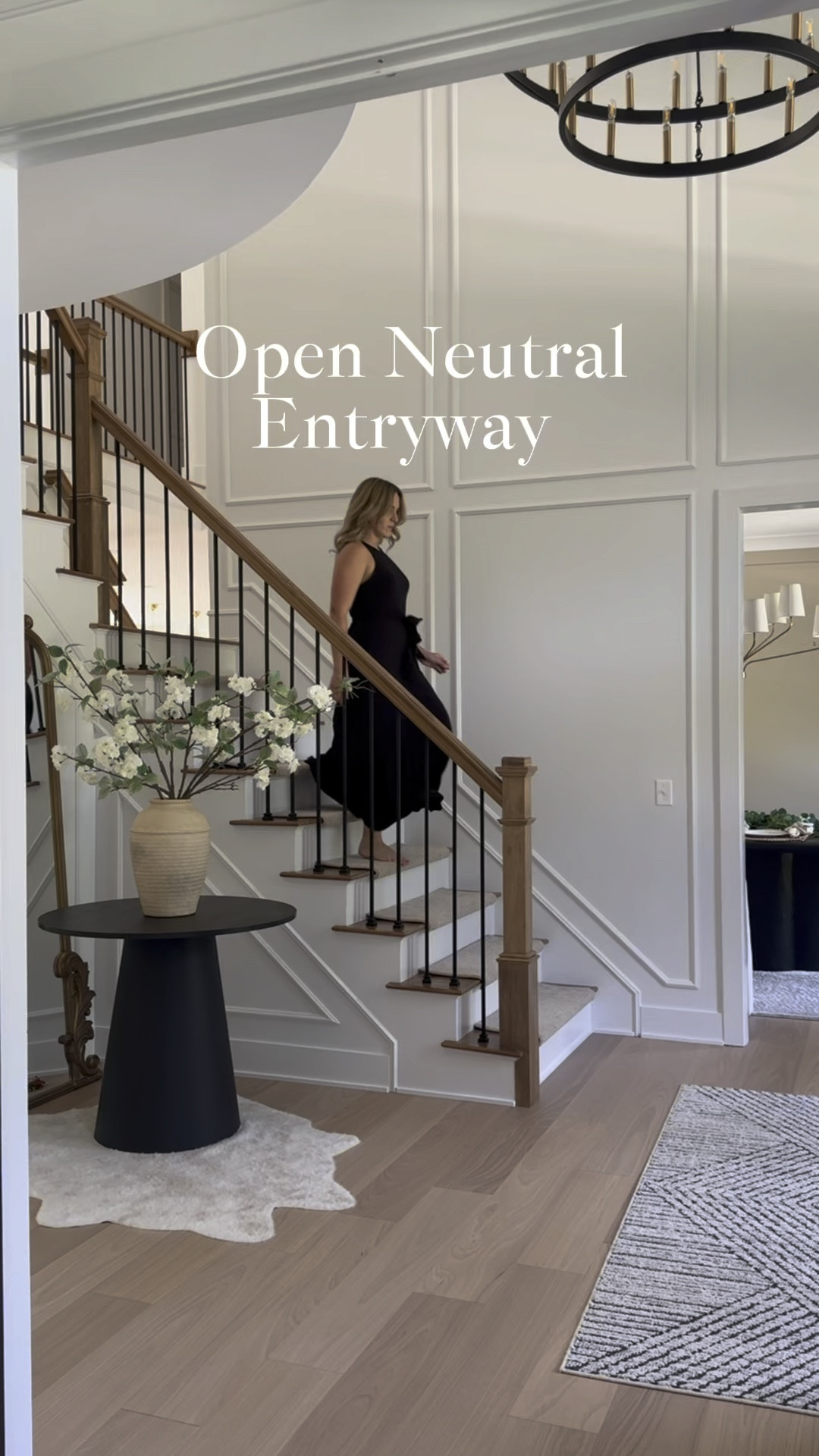 Shop my neutral entryway furniture and decor. 
- black pedestal table 
- geometric black and white rug
- double wagon wheel chandelier 
- white floral stems 
-neutral vases 

#LTKHome #LTKVideo