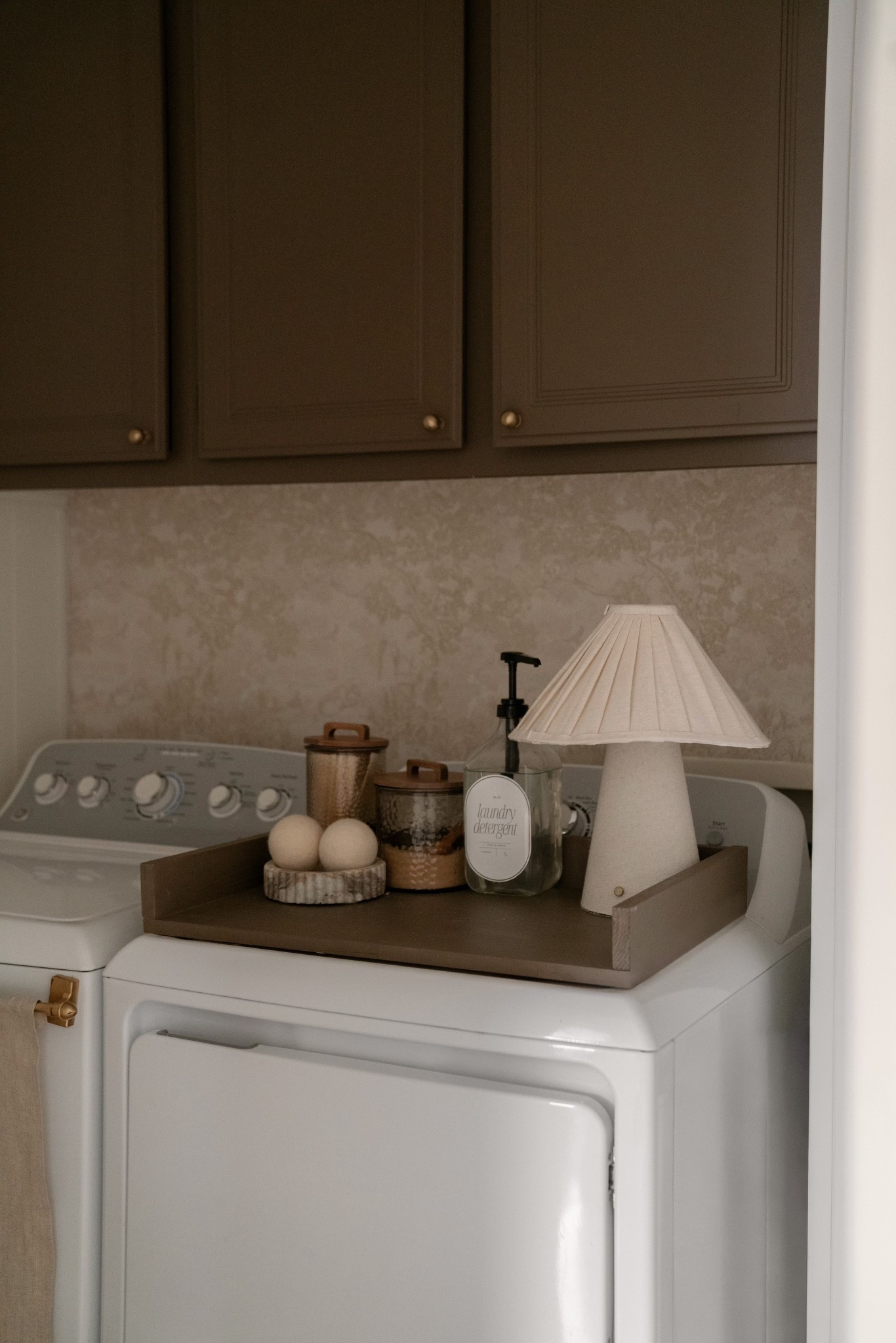 This little laundry room has become one of my favorite spaces in the house.
I linked the wallpaper and hardware on LTK — the cabinets are Northwood Brown by Benjamin Moore, and the walls are Greek Villa at 50% for that soft, warm contrast.

I made the tray & curtain myself, but it’s hung on a simple magnetic rod, which ended up being the easiest solution in here.
Everything I could link is saved on LTK for you.