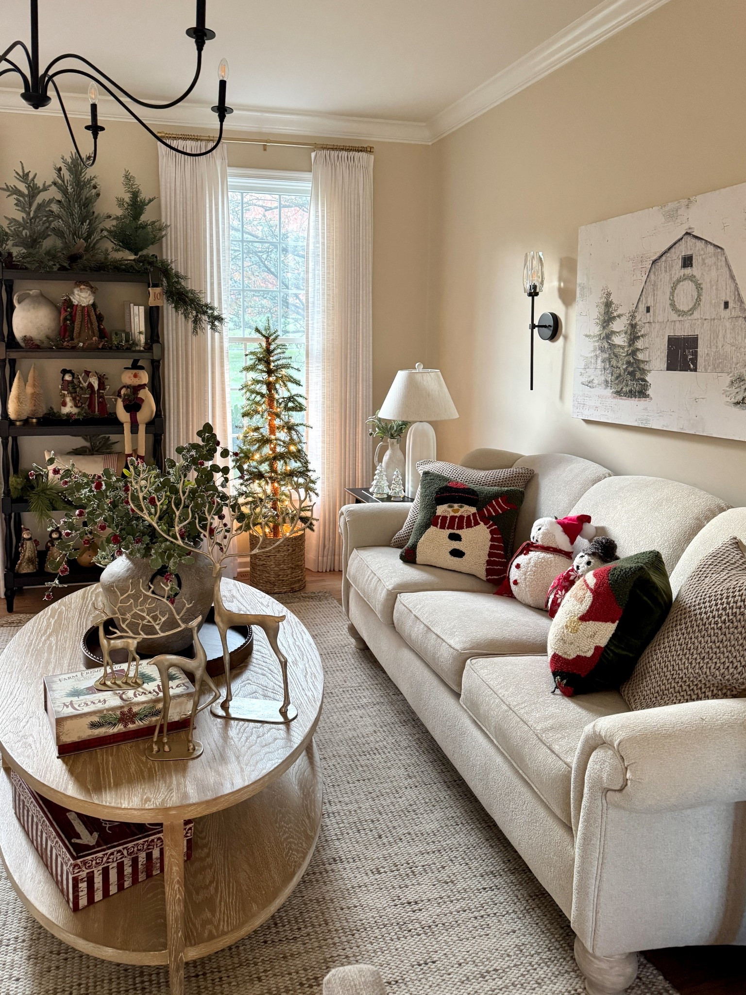 Living room decor and styling. Pretty Christmas barn print. 5 shelf onyx bookshelf. 4’ pine tree.  Trio of gold deer. Electric wall sconces. The cutest snowman and snow girl! Solid wood oval coffee table. Tabletop trees and more  

#LTKHoliday #LTKHome