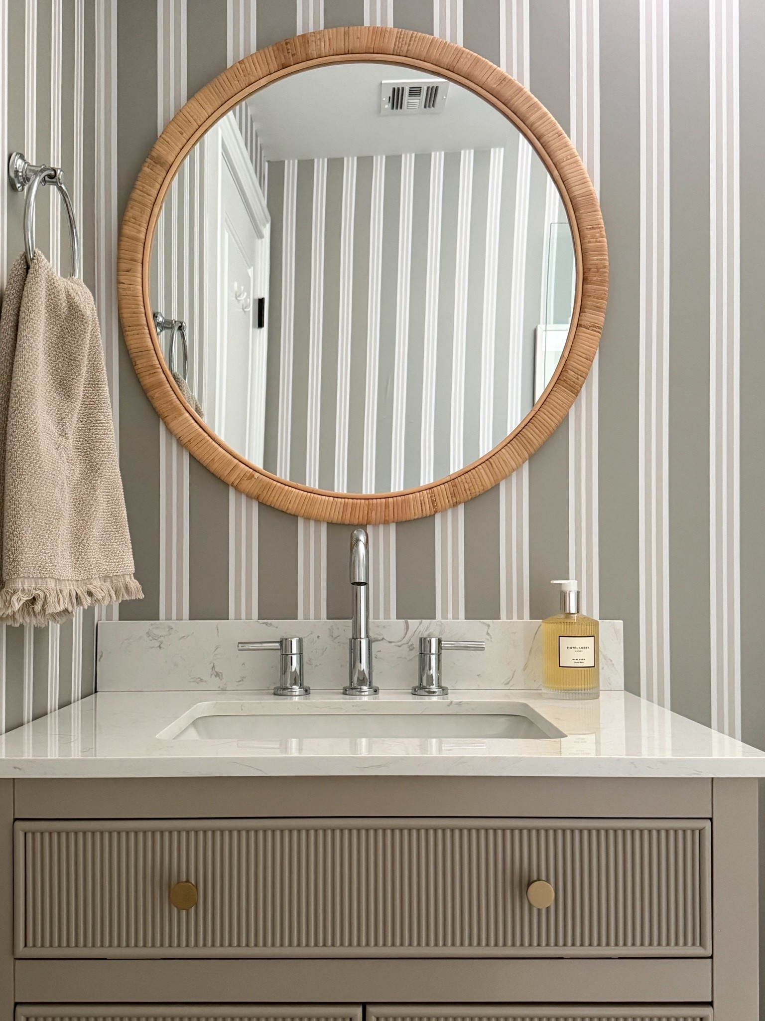 This powder room is the perfect example of how thoughtful details can transform a small space. The woven round mirror, striped wallpaper, fluted vanity, and warm brass accents create a look that feels classic, coastal, and elevated.

powder room decor, bathroom design ideas, striped wallpaper, round woven mirror, bathroom vanity, small bathroom inspiration, brass bathroom hardware, coastal bathroom decor, timeless home design, bathroom makeover, neutral interiors, girlonthehudson

#LTKHome #LTKSeasonal #LTKdayinmylife