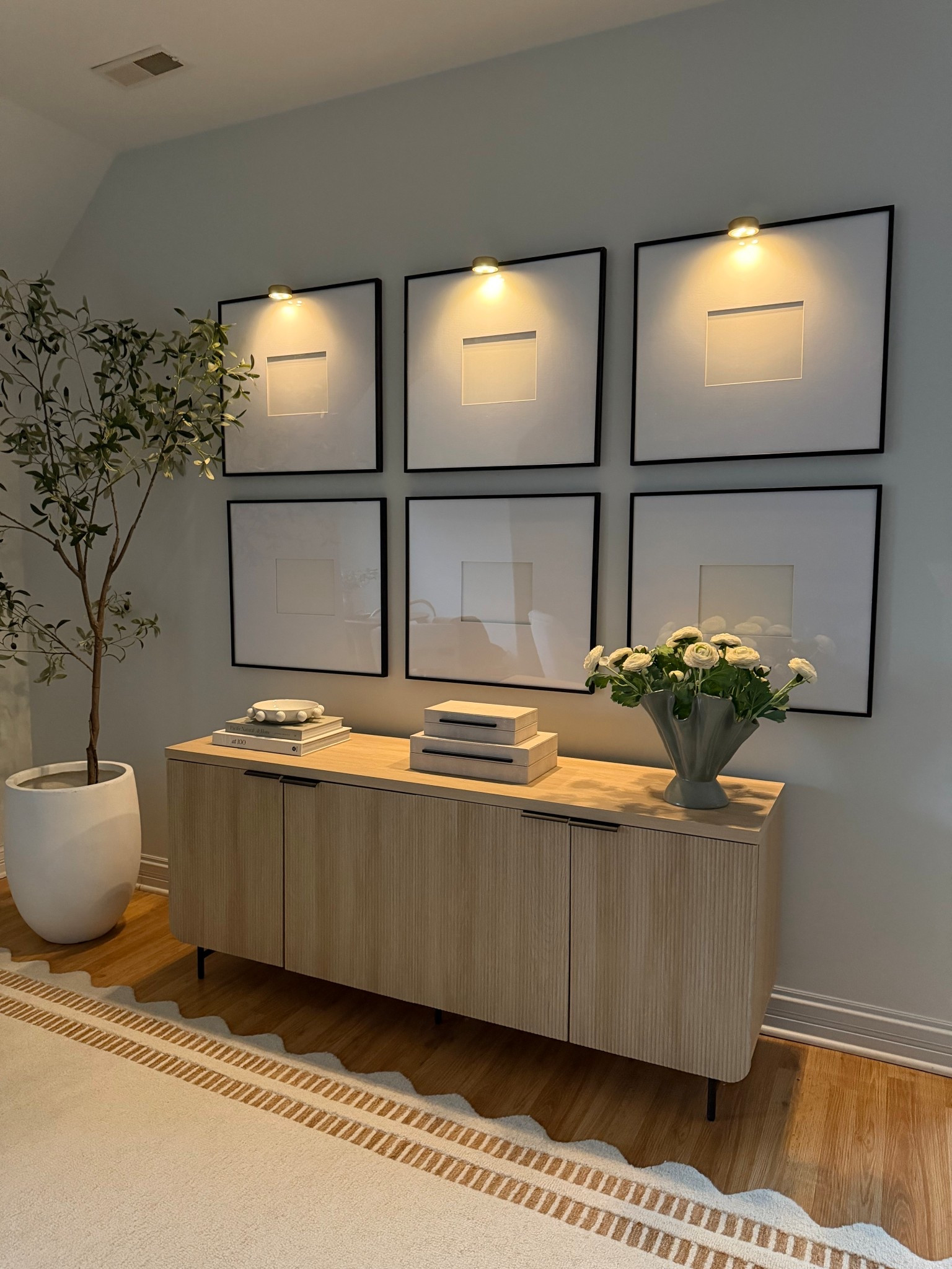 One of my favorite ways to elevate a gallery wall is adding small picture lights above the frames ✨ It creates a warm glow in the evenings and makes the whole space feel more intentional and layered. Styled this console with a few simple decor pieces — books, decorative boxes, and fresh flowers. Linking the picture lights and decor used here.

#LTKHome