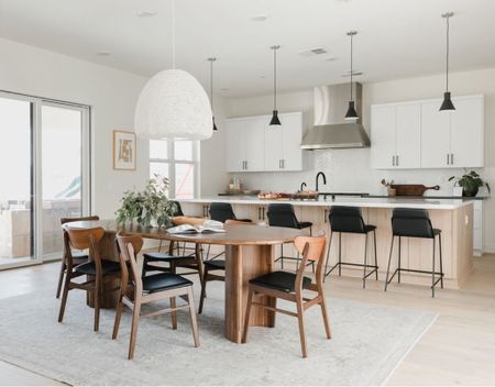 Modern coastal dining room with an oblong dining table and coordinating curved dining chairs with leather upholstery. A fun oversized pendant light  over the table to center the space. 

#diningroom #interiordesign #homedesign

#LTKSeasonal #LTKhome #LTKunder100