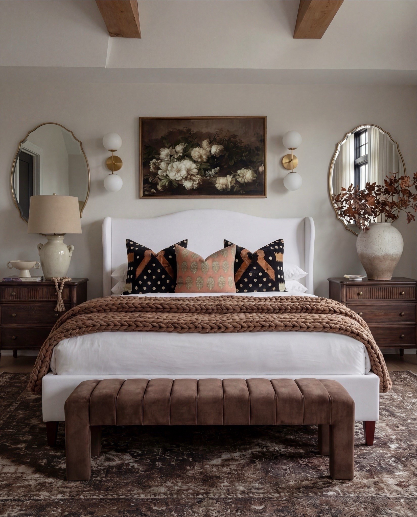 This bedroom feels warm, layered, and quietly refined. The soft upholstered bed keeps the space light and serene, while rich wood tones, earthy textiles, and vintage-inspired accents add depth and contrast. Sculptural lighting, warm brass details, and cozy textures create a balance between elegance and comfort — a space that feels elevated yet deeply livable.

The styling leans into warm neutrals and organic materials — chunky knits, aged woods, soft linen layers, and curated decorative moments that give the room a collected, timeless atmosphere.

Shop the Look:
• White upholstered wingback bed frame
• White cotton duvet cover + pillow shams
• Textured throw pillows (rust + black patterned)
• Chunky knit throw blanket (warm brown)
• Vintage-style brown area rug
• Dark wood nightstands with brass knobs
• Ceramic table lamp (neutral glaze)
• Brass globe wall sconces
• Framed floral artwork (muted tones)
• Arched brass wall mirrors
• Upholstered bench at foot of bed (camel brown)
• Cream accent chair with wood arms
• Black fluted dresser with brass pulls
• Round black fluted end table 
•Fecor books 
• Large ceramic floor vase (earthy clay tone)
• Decorative wood bead garland
• Sheer white curtain panels
•Round decor bowl tray 
•Wood jewellery box 
•Terracotta bowl 
@Wayfair 



#LTKHome #LTKSaleAlert