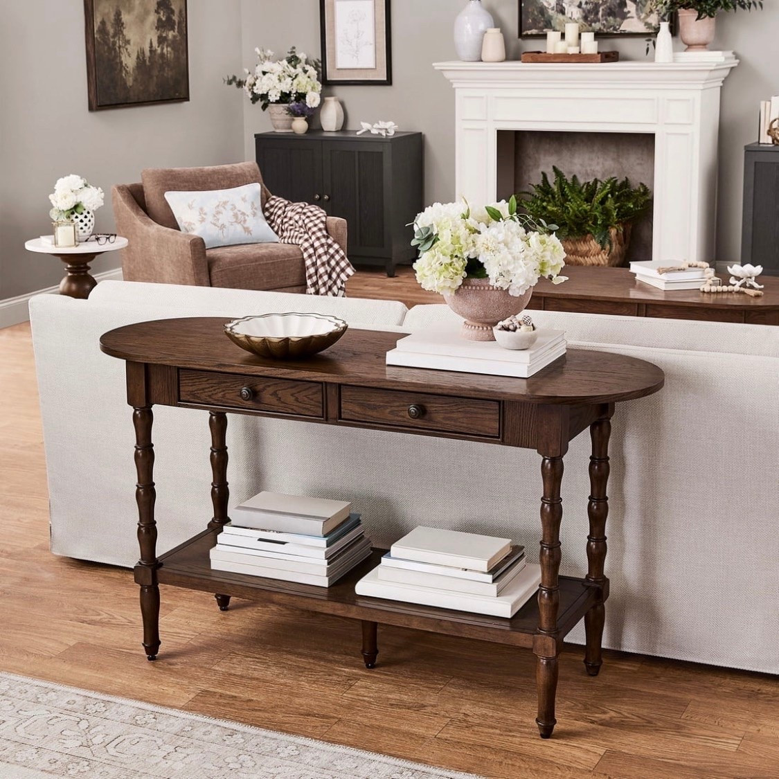 This My Texas House console table brings farmhouse style and everyday function to your home. The 54 in oval top gives you room to style lamps, framed photos, and seasonal decor while keeping daily essentials close at hand. Two drawers help keep small items tucked away, and the lower shelf adds open space for baskets, books, or accents. A warm brown finish and turned wood legs give the piece a classic look that feels inviting in an entryway, living room, or accent space. Place it behind a sofa or along a wall to add display space, storage, and a finished look. Designed for daily use, this table combines practical storage with a timeless shape that works easily with a farmhouse-inspired room

#LTKSeasonal #LTKHome