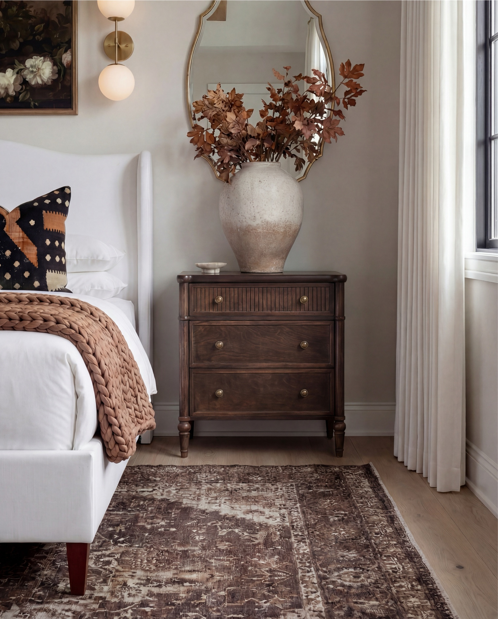 Shop the Look:
• White upholstered wingback bed frame
• White cotton duvet cover + pillow shams
• Textured throw pillows (rust + black patterned)
• Chunky knit throw blanket (warm brown)
• Vintage-style brown area rug
• Dark wood nightstands with brass knobs
• Ceramic table lamp (neutral glaze)
• Brass globe wall sconces
• Framed floral artwork (muted tones)
• Arched brass wall mirrors
• Upholstered bench at foot of bed (camel brown)
• Cream accent chair with wood arms
• Black fluted dresser with brass pulls
•Ceramic beige decor bowl
•Decor wood beads 
•Decor book
• Large ceramic floor table vase (earthy clay tone)
• Decorative wood bead garland
• Sheer white curtain panels
•Decor tray
•Hurricane candle holder
Wood Jewelery box 
@Wayfair 

#LTKSaleAlert #LTKHome