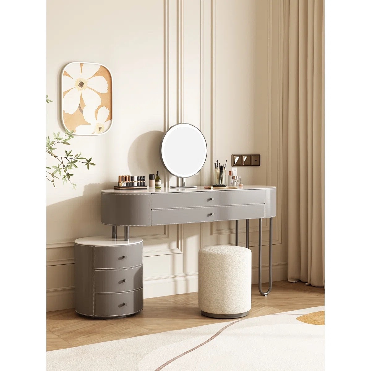 This vanity setup from Wayfair feels more like a little dressing area than a basic makeup desk. The soft taupe finish, saddle leather-look top, curved drawer storage, slim stainless steel support, and round dimmable LED mirror all work together so nicely. The matching cream stool keeps it soft and simple, and I like how the floral wall art, greenery, neutral rug, and long curtains make the whole corner feel really calm. The reversible installation is a nice detail too if you’re working around a specific bedroom layout.