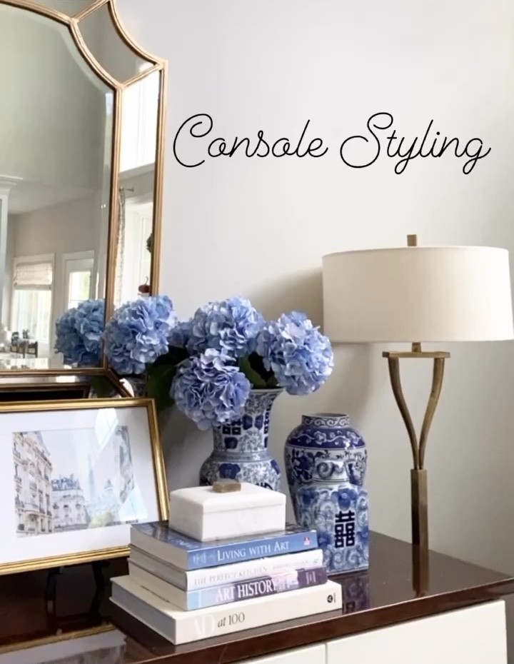 Console styling in my great room using coffee table books, blue and white ginger temple jars, decorative box, framed Paris print and my favorite gold wall mirror 

#interiorstyling #traditionaldesign #mirror #coffeetablebooks #interiordesign 

#LTKhome #LTKstyletip #LTKsalealert
