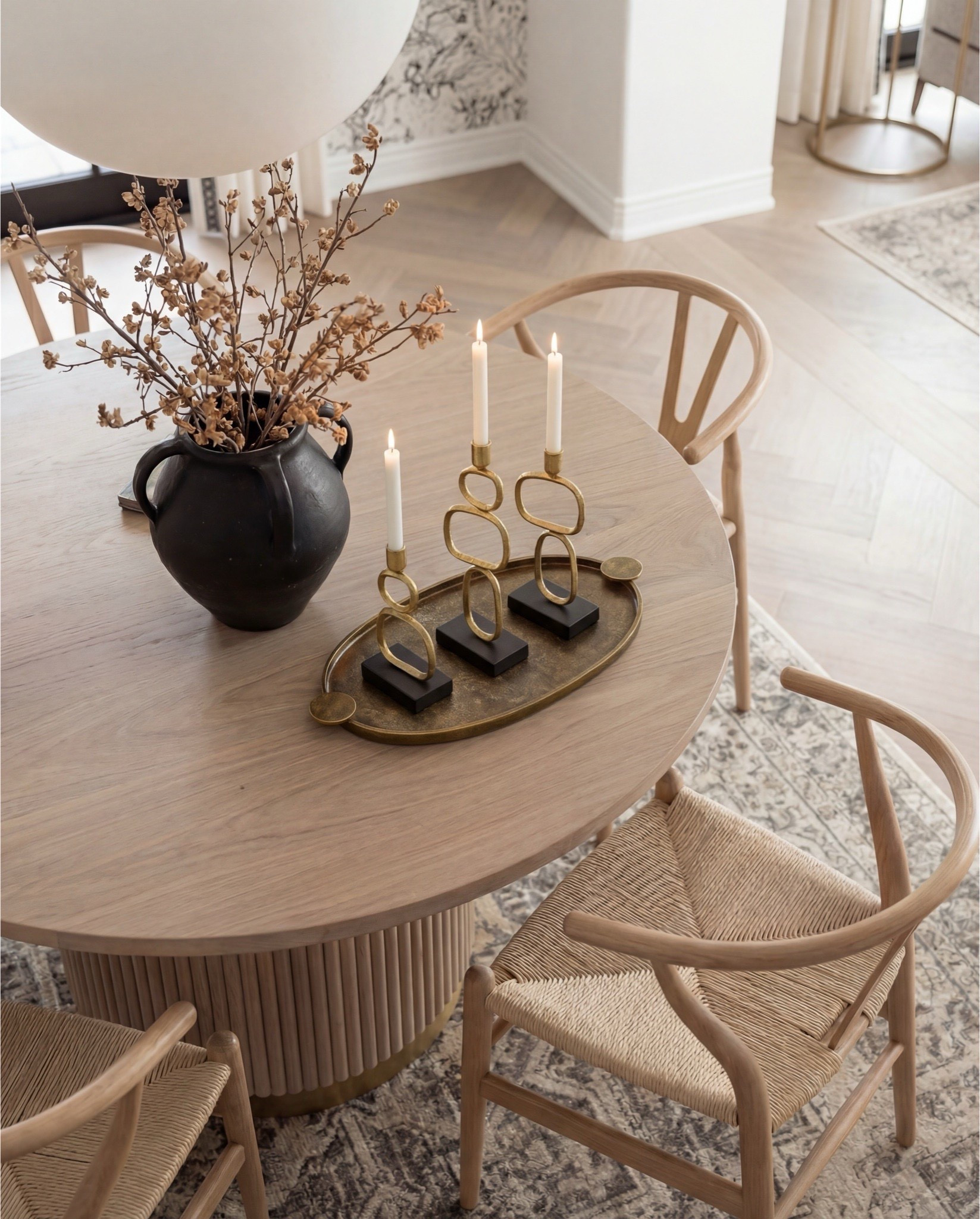 Round wood dining table, wood weave dining chairs, oak console buffet, beige traditional rug, black vase, white table lamp. Brass tray, candle holder brass.  

#LTKHome #LTKSaleAlert