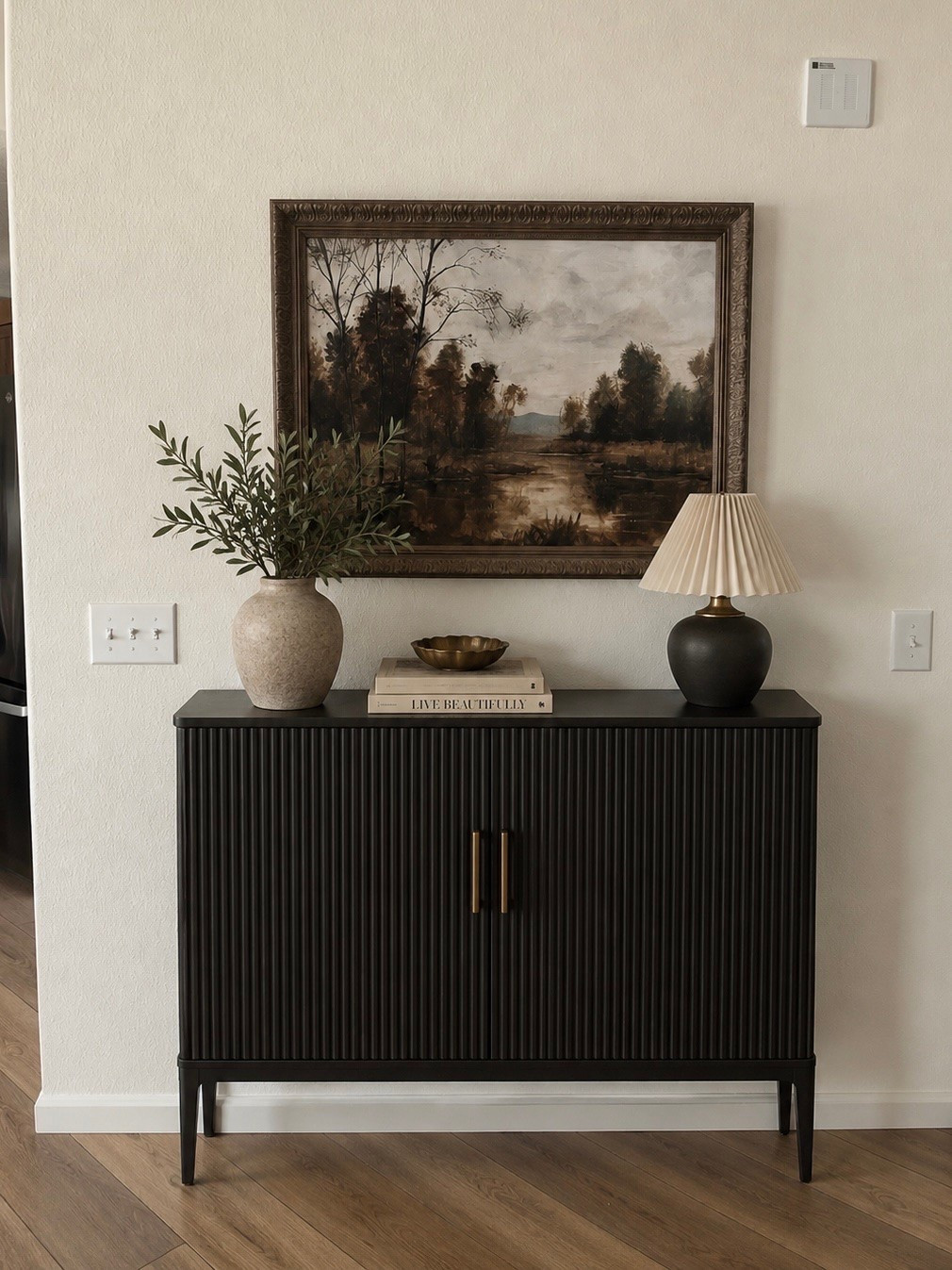 A warm and moody entryway moment 🖤 I paired a black fluted cabinet with vintage-inspired artwork, warm neutrals, aged brass and organic greenery for a collected, transitional look. 

Wall art is from Hobby Lobby

#LTKHome