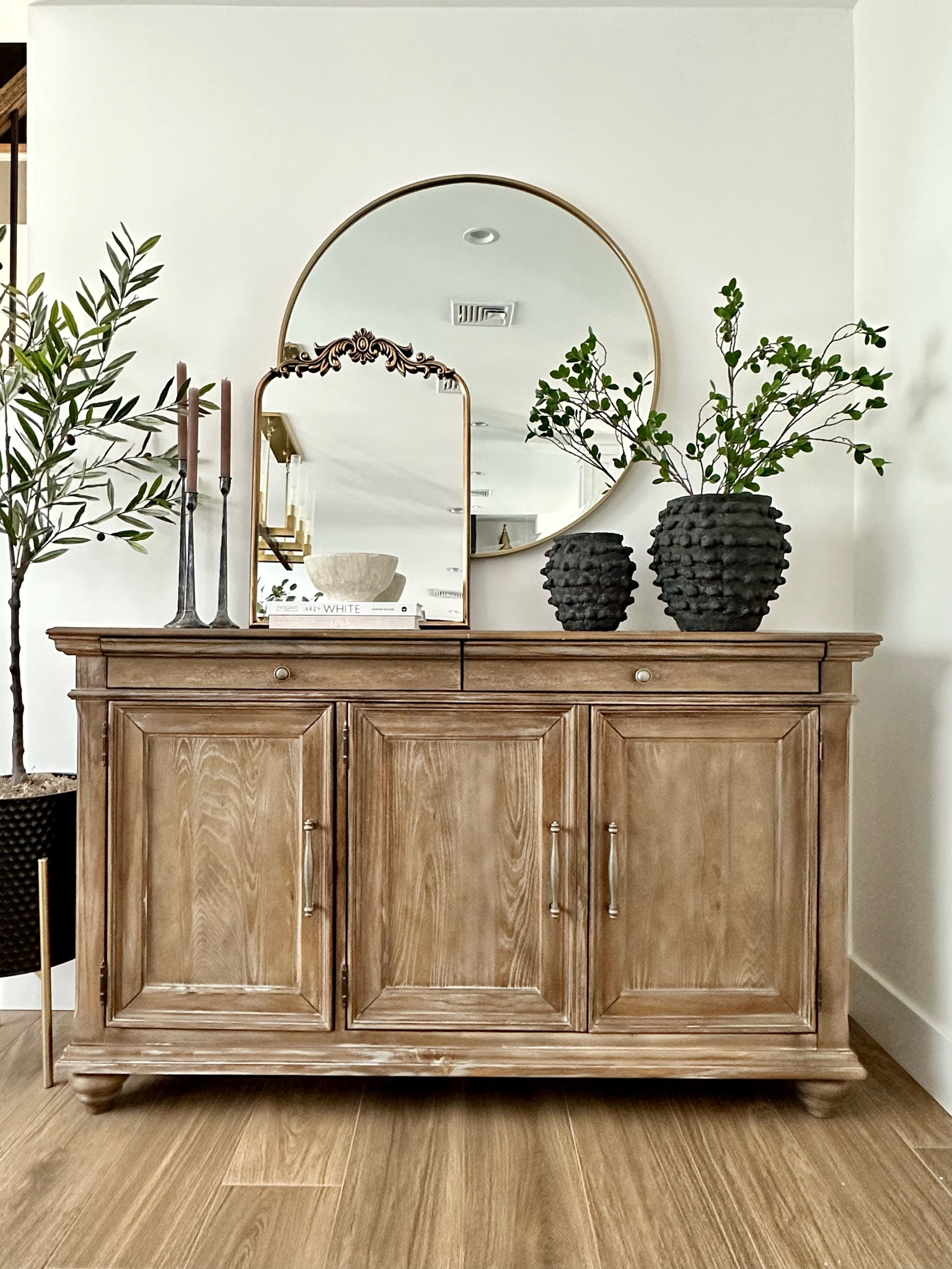 Buffett table styling, sideboard decor, designer dupe mirror, anthro mirror, primrose mirror, dining room, baroque mirror, round mirror, anthropology vase, bubble vase, greenery, stems, artisan pottery barn bowl, metal tapered candleholder, white coffee table book, linen book, olive tree

#LTKFind #LTKhome