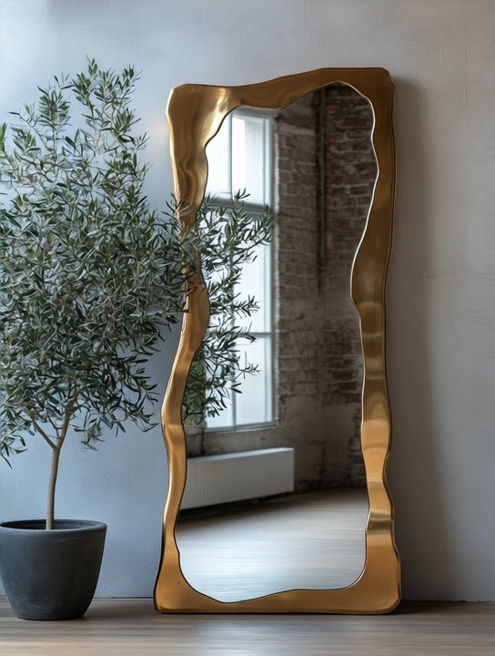 A sculptural mirror with an irregular shape instantly turns any corner into a design moment. Whether you choose a gold frame for a touch of warmth and glamour or a wooden frame for a more natural, organic feel, this style of mirror adds movement and character without feeling trendy. Paired with a simple, elegant olive tree, the look feels balanced, calm, and thoughtfully curated. This setup works beautifully in a living room, bedroom, hallway, entryway, or even an empty corner that needs intention. The combination of soft curves, natural greenery, and refined materials creates a timeless statement that elevates your home while still feeling relaxed and livable.
#homedecor #statementmirror #quietluxury 

 #LTKHome