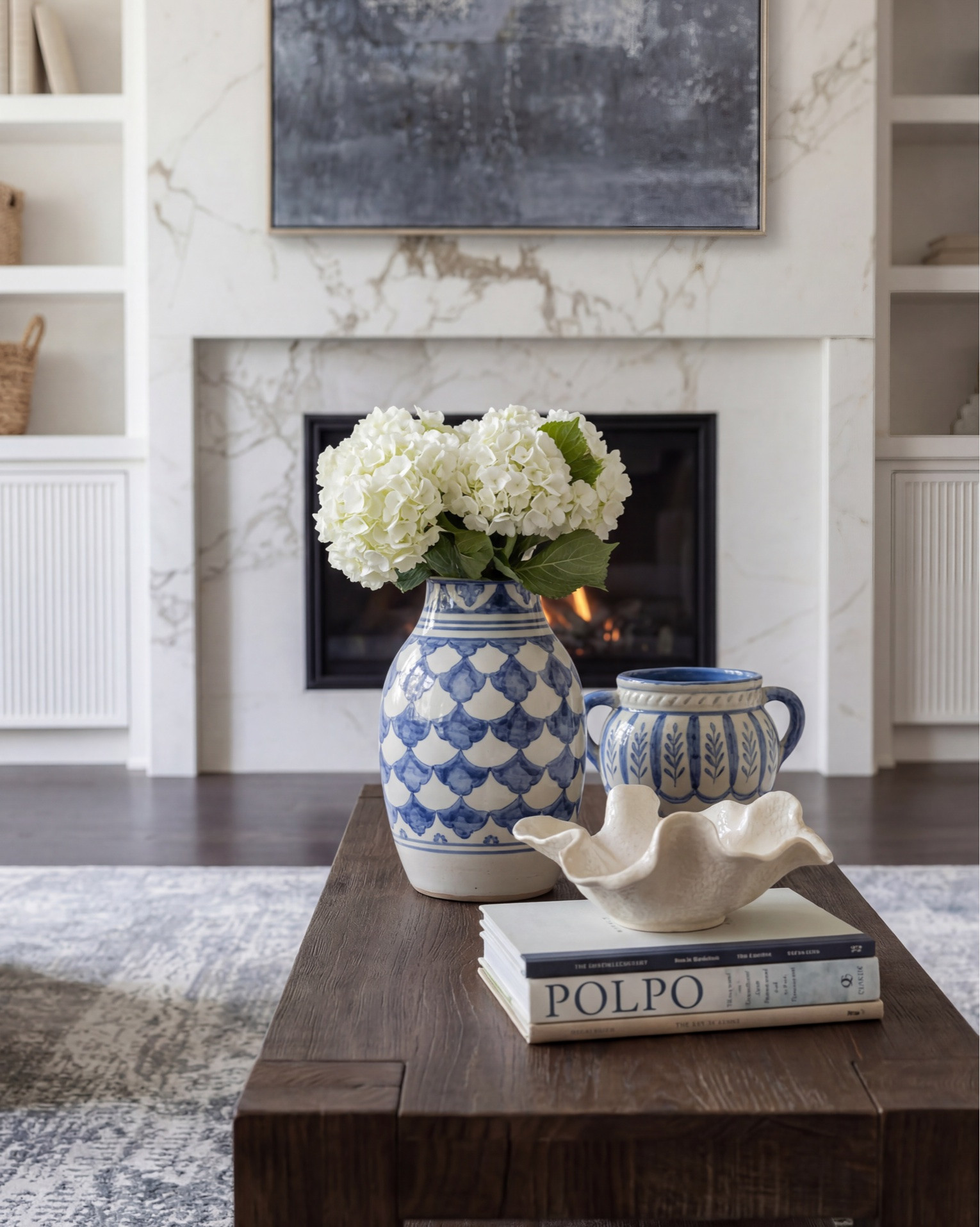 Layered transitional living room inspiration with luxe marble fireplaces, moody floral wallpaper, dark wood beams, boucle accent chairs, and designer lighting details. Shop the look for a cozy modern organic home with high-end furniture, neutral decor, blue accents, brass lighting, textured rugs, and timeless statement pieces. Perfect inspiration for anyone searching for transitional style living rooms, modern farmhouse decor, marble fireplace ideas, designer coffee tables, and curated home accessories. 

Shop this space: • Marble fireplace surround • Dark wood ceiling beams • Brass chandelier lighting • Boucle accent chairs • White slipcovered sofa • Blue patterned throw pillows • Dark wood coffee table • Abstract framed artwork • Textured neutral area rug • Ceramic table lamps • Built-in shelving decor • Decorative woven baskets • Floral wallpaper mural • Fringe ottomans • Fluted console table • Brass wall sconces • Ribbed cabinetry details • Marble slab backsplash • Glass cabinet fronts • Wine fridge built-in • Blue and cream vintage style rug • Modern ceramic vases • Coffee table styling books • Neutral cozy throw blankets

#LTKsale #LTKhome #LTKstyletip