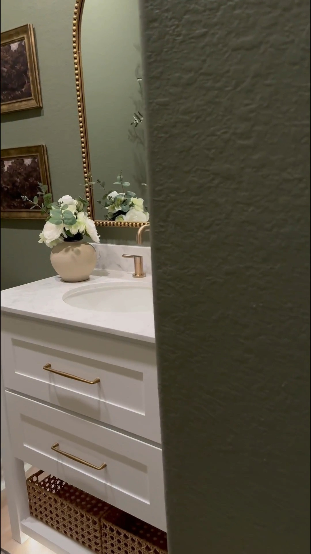 If you’re considering painting your powder room green, I’m telling you, THIS might be the perfect color for you … go for it! 

I used flat finish for the walls and painted the baseboards in satin finish… 

I’ll be honest, I was apprehensive at first … I even paintings the ceiling 😬 believe it our not, it made the room feel larger! 

I chose brass finishes bc I really wanted the space to have a vintage feel… well, modern vintage…??? If that’s a thing 😆.. 

The mirror is 30x40 inches… 

I added a new light fixture and it now faces upwards … which made that wall feel taller 

I wasn’t in love with this builder grade vanity tbh😆, matter-fact, I wanted to change it… it wasn’t functional …but now i wanna keep it lol 😂… I added brass hardware, these cute baskets from Walmart, led light strips on the bottom and now it’s a whole new unit….. you can even add battery powered/rechargeable/plug in led light strips .. whatever fits your lifestyle 

Ok let’s talk about this stunning planter!!! …. You know I love me an olive tree 😆… and I wanted something tell and slim… this planter was the perfect for plus it added to the moodiness 🥰

I am in love with this space… I wanted to create a vintage-cottagy feel in this powder room, while the rest of the home feels modern. #LTKVideo

#LTKHome #LTKStyleTip