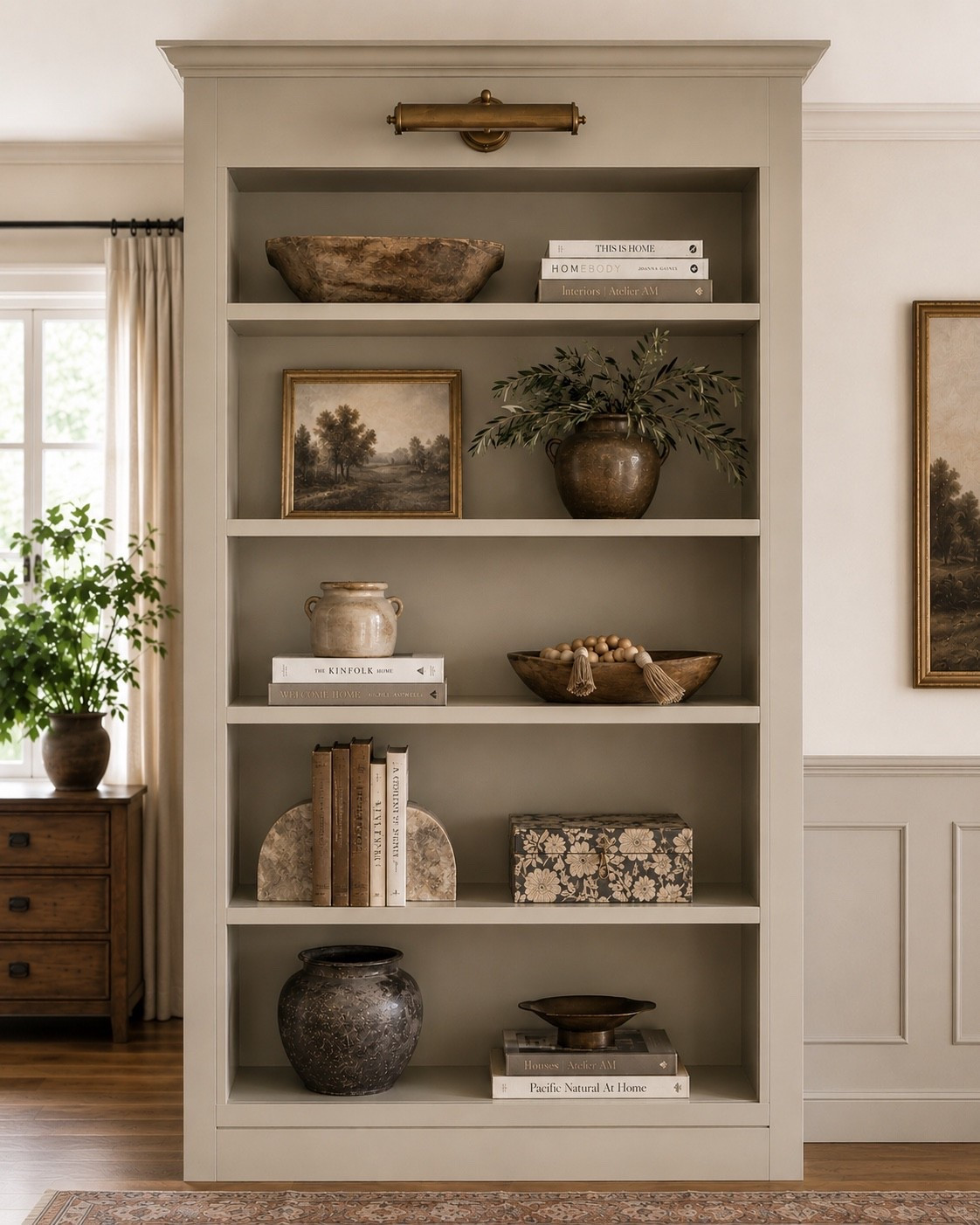Bookshelves can hold quite a bit without feeling cluttered when there’s enough variation—and enough empty space—between everything.

For this shelf, I mixed old books with artwork, pottery, wood, greenery and a few smaller decorative pieces, changing the height and scale from shelf to shelf instead of trying to make each one perfectly symmetrical. I also like letting some pieces stand on their own rather than filling every open spot. That little bit of breathing room is what keeps a collected bookshelf from starting to feel busy.

And you definitely don’t need these exact pieces to get the same look. I curated similar artwork, pottery, bowls, books and vintage-inspired decor that would give you the same warm, collected feeling. Everything I found is linked here to shop.

#LTKHome