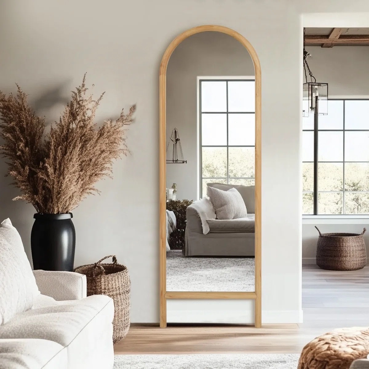 This arched full length mirror adds such a warm, natural touch to the room with its light wood frame. It pairs beautifully with the neutral sofa, textured rug, and woven baskets to create a calm and inviting space. Perfect for brightening a corner and making any room feel more open. #homedecor #archedmirror #neutralhome #cozystyle
