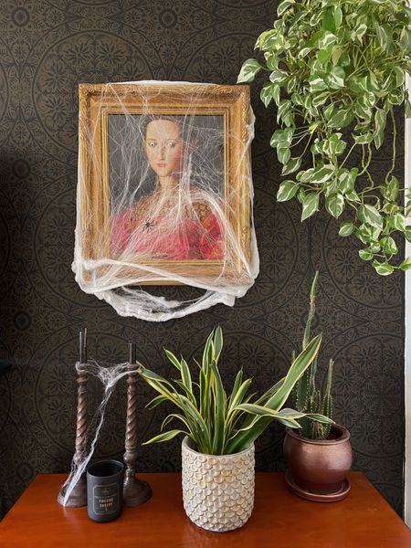 Spooky chic Halloween decor with a fun vintage style portrait print.  Add googley eyes and spider webs of course! Vintage candlesticks, black wallpaper and lots of houseplants complete the look.  

#LTKHalloween #LTKSeasonal #LTKfindsunder50