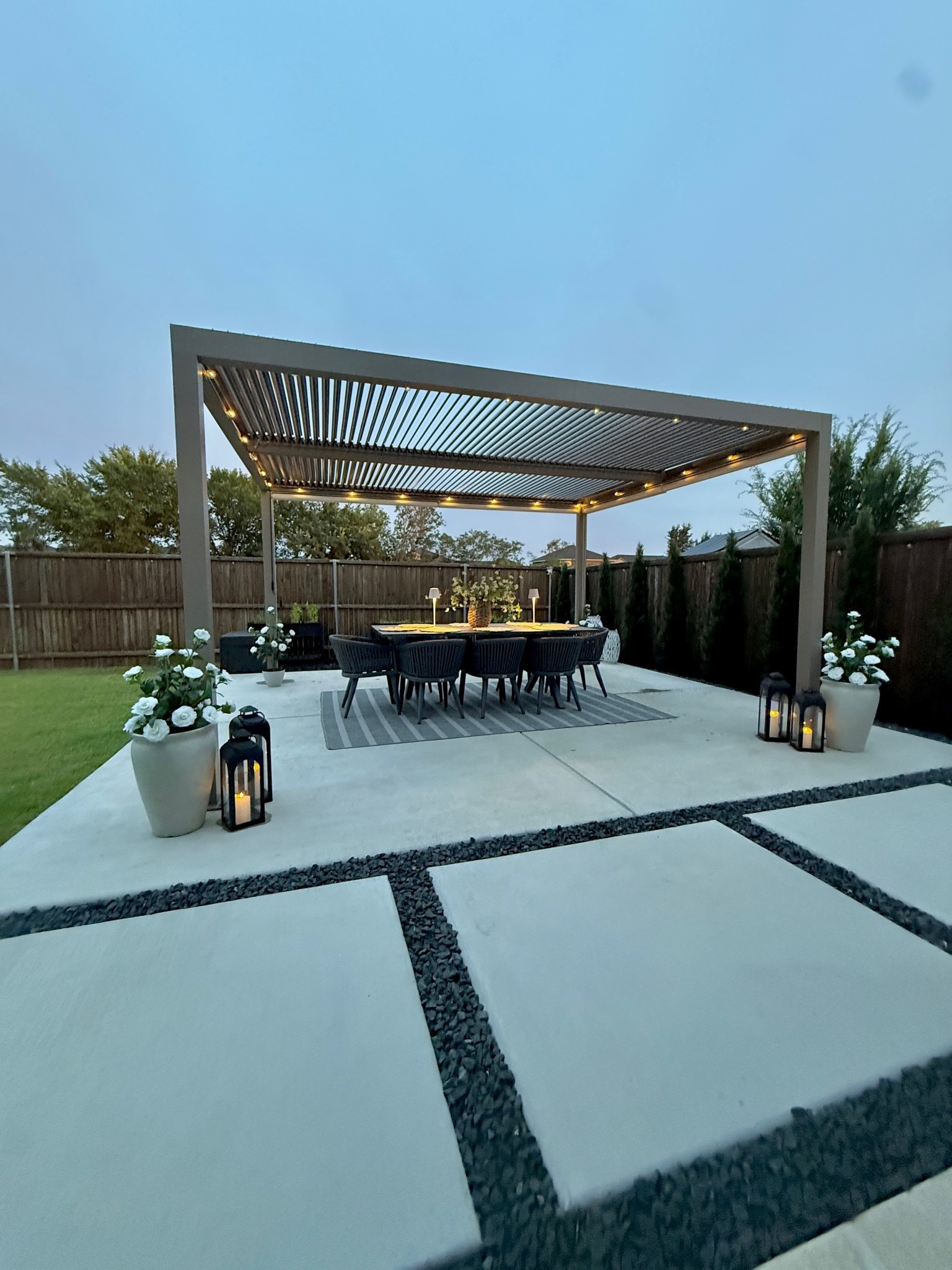 Cozy outdoor patio, pergola, outdoor dining table, faux trees 

This is the 12x14 purple leaf louvered pergola in color champagne. It goes in and out of stock frequently so if you've been eyeing it grab it while you can! 
@wayfair