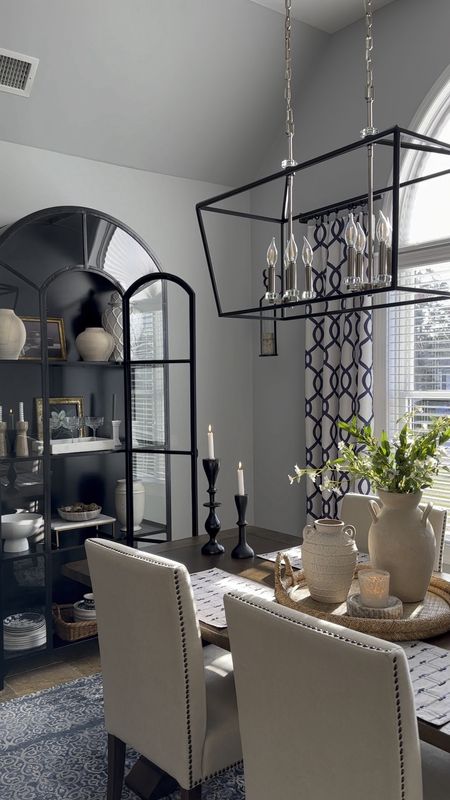 Dining space refresh. Black display cabinet, black light fixture, home decor accessories. Vases, candleholders, tray, stems, greenery, wood table, upholstered dining chairs, olive tree, sconce set, window treatments, blue area rug. 

#LTKsalealert #LTKhome #LTKfindsunder50