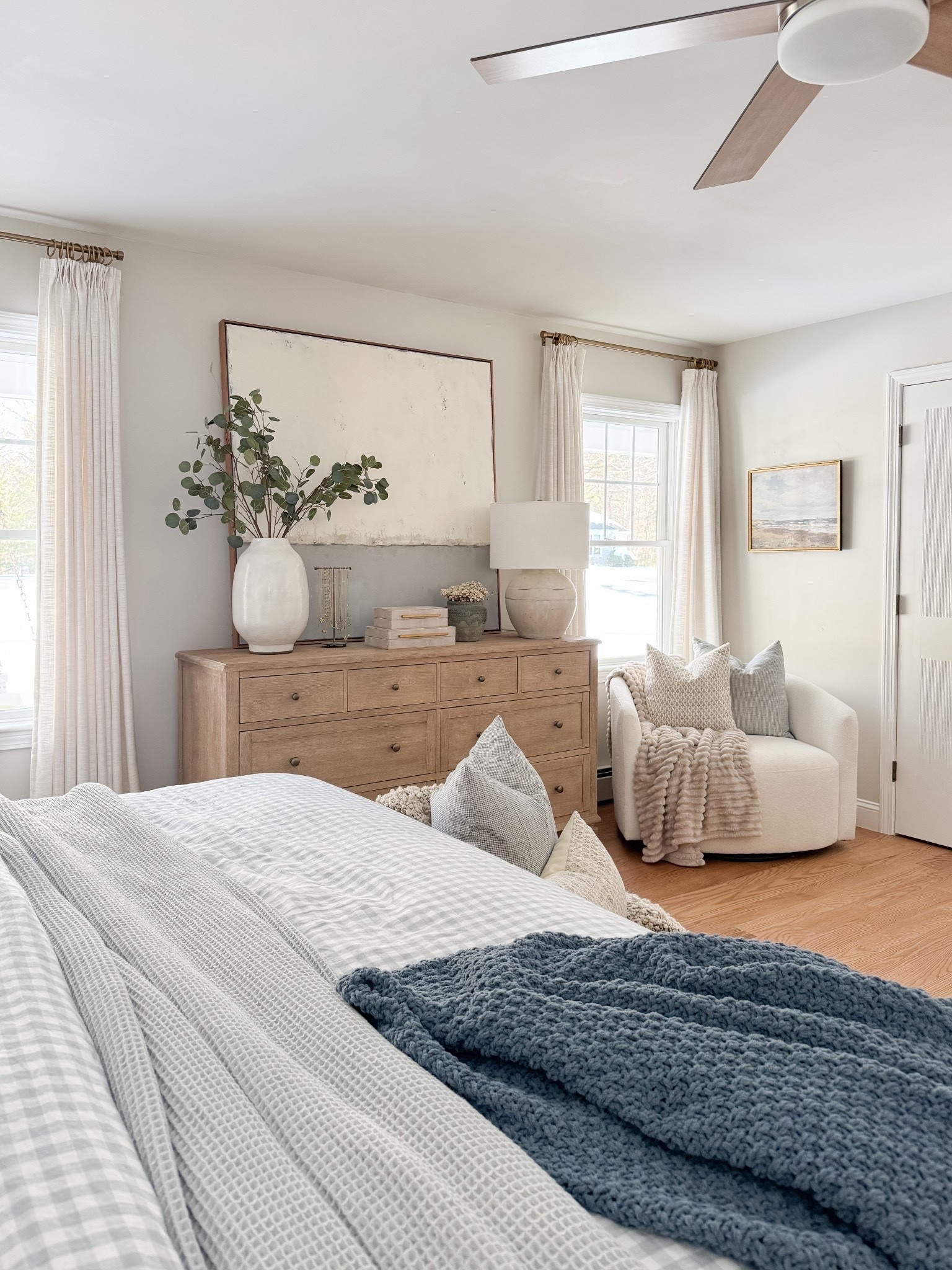 Neutral coastal bedroom with gingham bedding, layered throw blankets, textured knit coverlet, and soft patterned pillows. Light wood nightstands and white table lamps create a calm, layered spring bedroom look. 
gingham bedding, neutral bedroom decor, layered bedding, summer bedding, coastal bedroom, throw blanket, knit coverlet, patterned pillows, light wood nightstands, white table lamps, cozy bedroom, serene bedroom style, sherri calnan home

#LTKHome