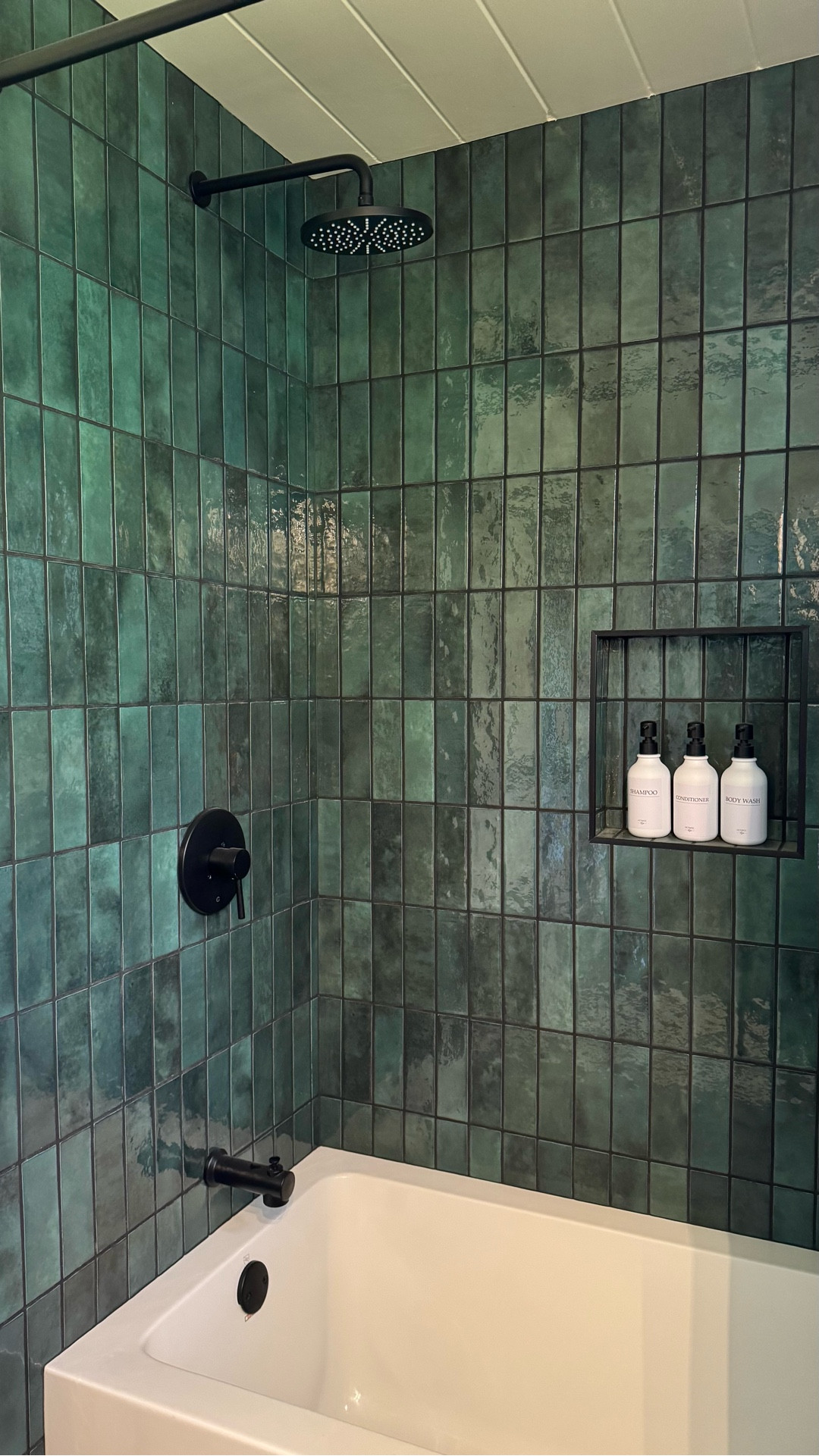 Small bathroom renovation. Modern tub. Modern shower tile. Green tile. Zellige tile. Cabin bathroom. Black shower head. Bathroom vanity. Organic mirror. Irregular mirror. Toilet seat upgrade. Adhesive toilet paper holder. Vanity light. Shampoo bottle. Bathroom bottles. Bathroom remodel.

#LTKHome